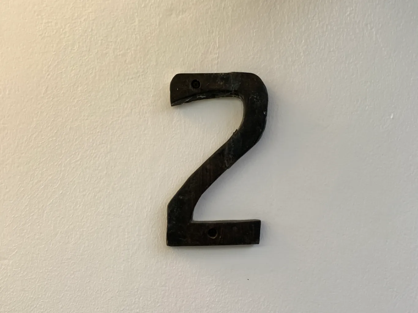 Close-up of a decorative number two displayed on a textured neutral background.