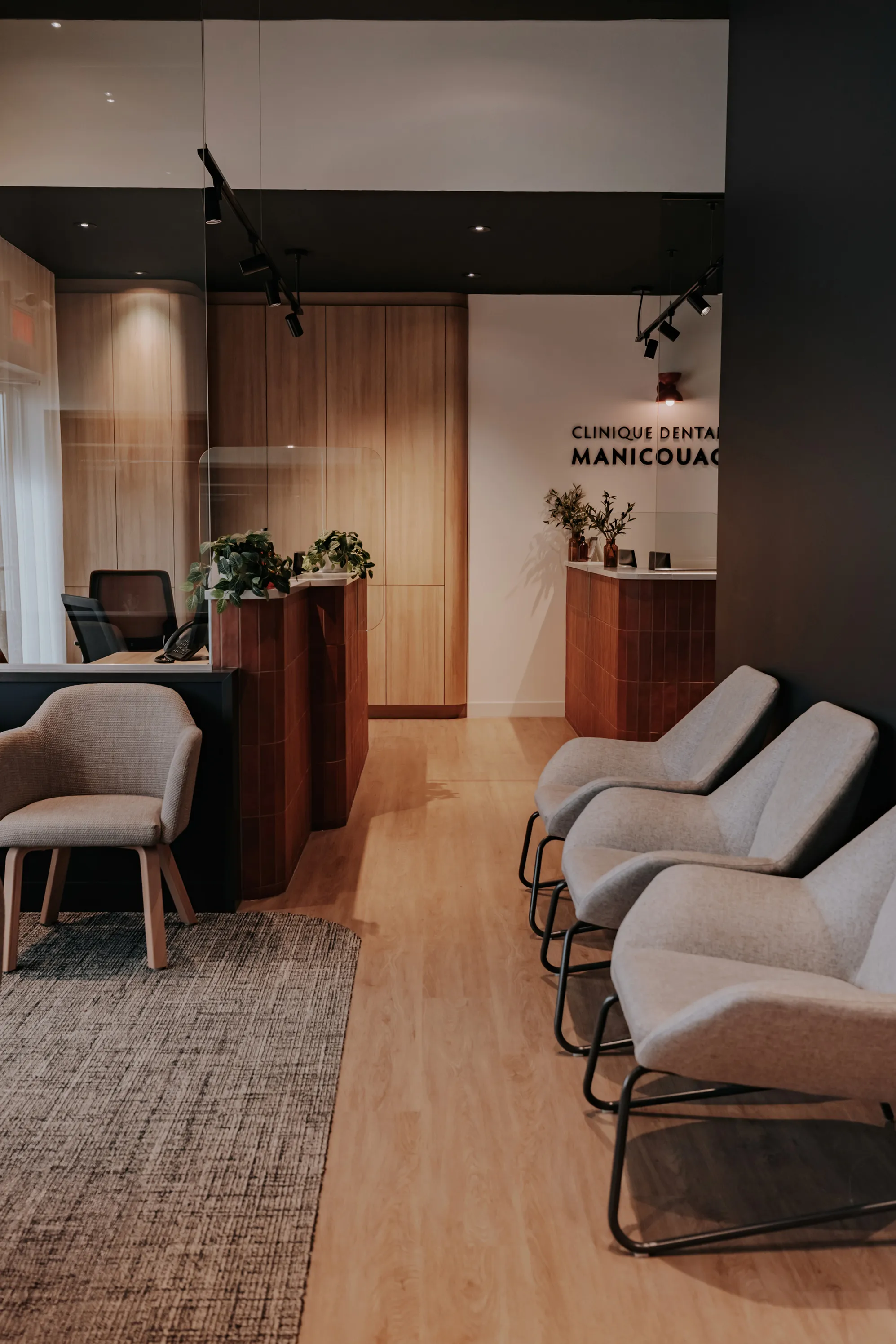 Salle d'attente de la Clinique dentaire Manicouagan avec fauteuils gris et comptoir d'accueil