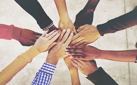 A diverse group stacking their hands together in camaraderie.