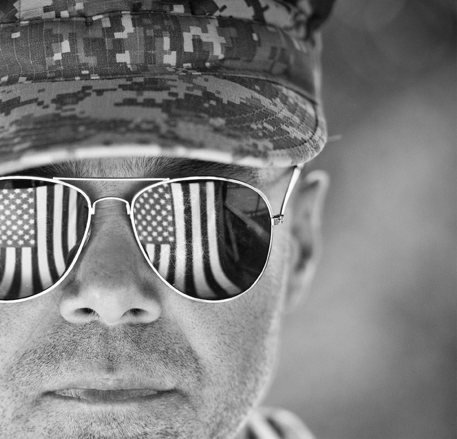 A veteran in aviator sunglasses reflecting the American flag.