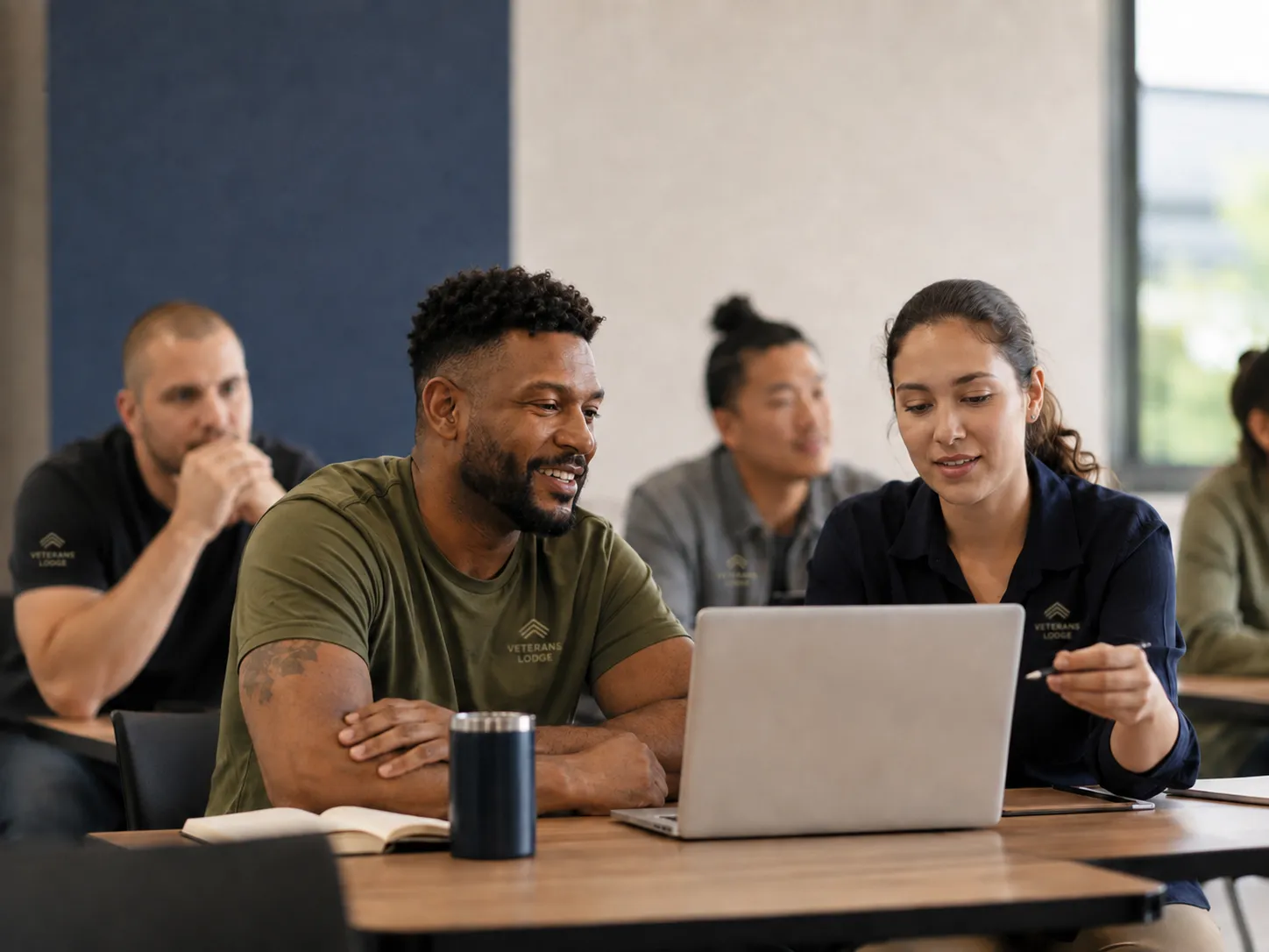Veterans learning together at laptops in a classroom.