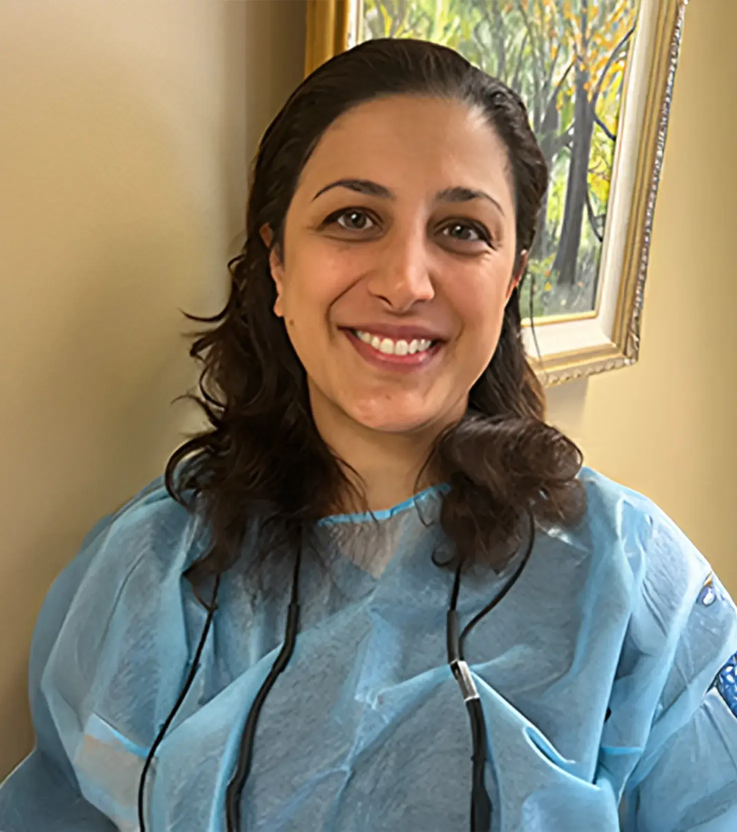Smiling woman in a blue dental uniform with a dental tool around her neck.