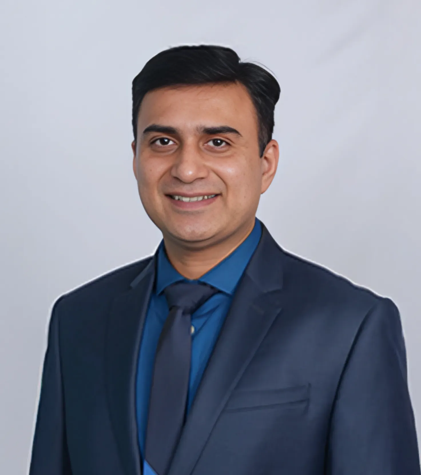 Smiling man in a blue suit and tie, against a plain background.