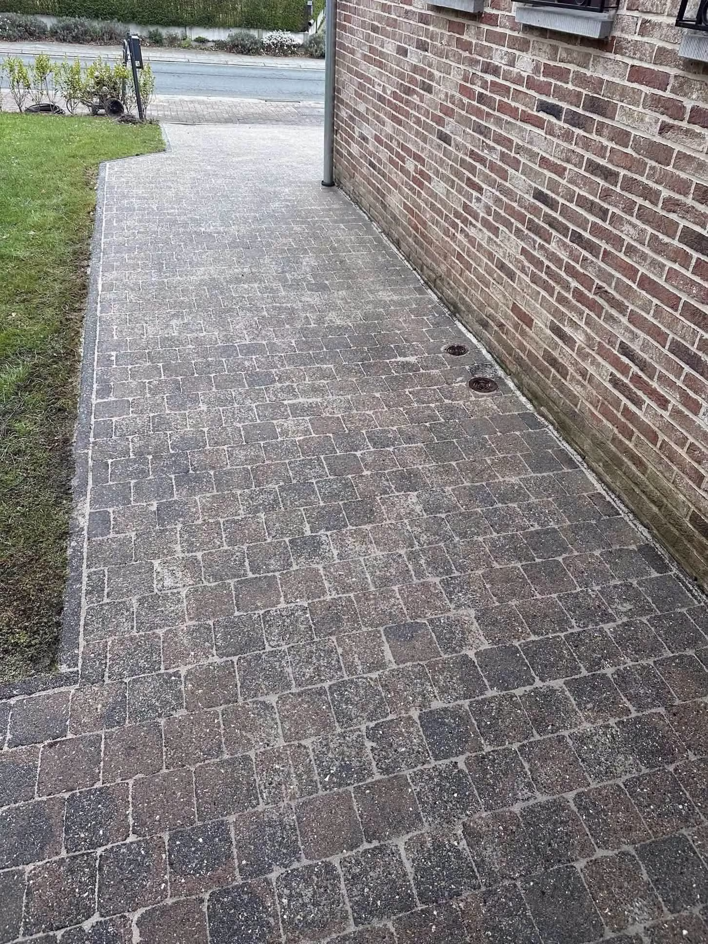 Allée en pavés nettoyée le long d'une façade en briques