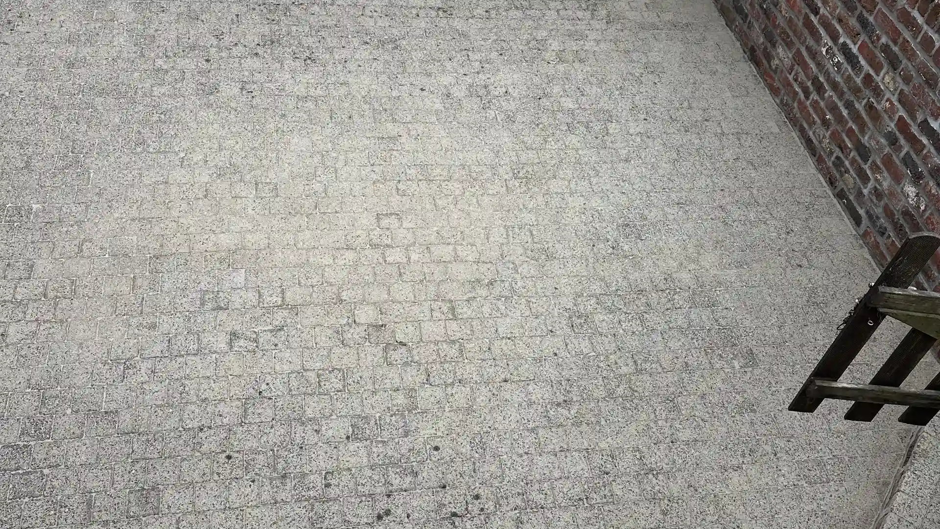 Cour en petits pavés gris clair le long d'un mur en briques, après nettoyage