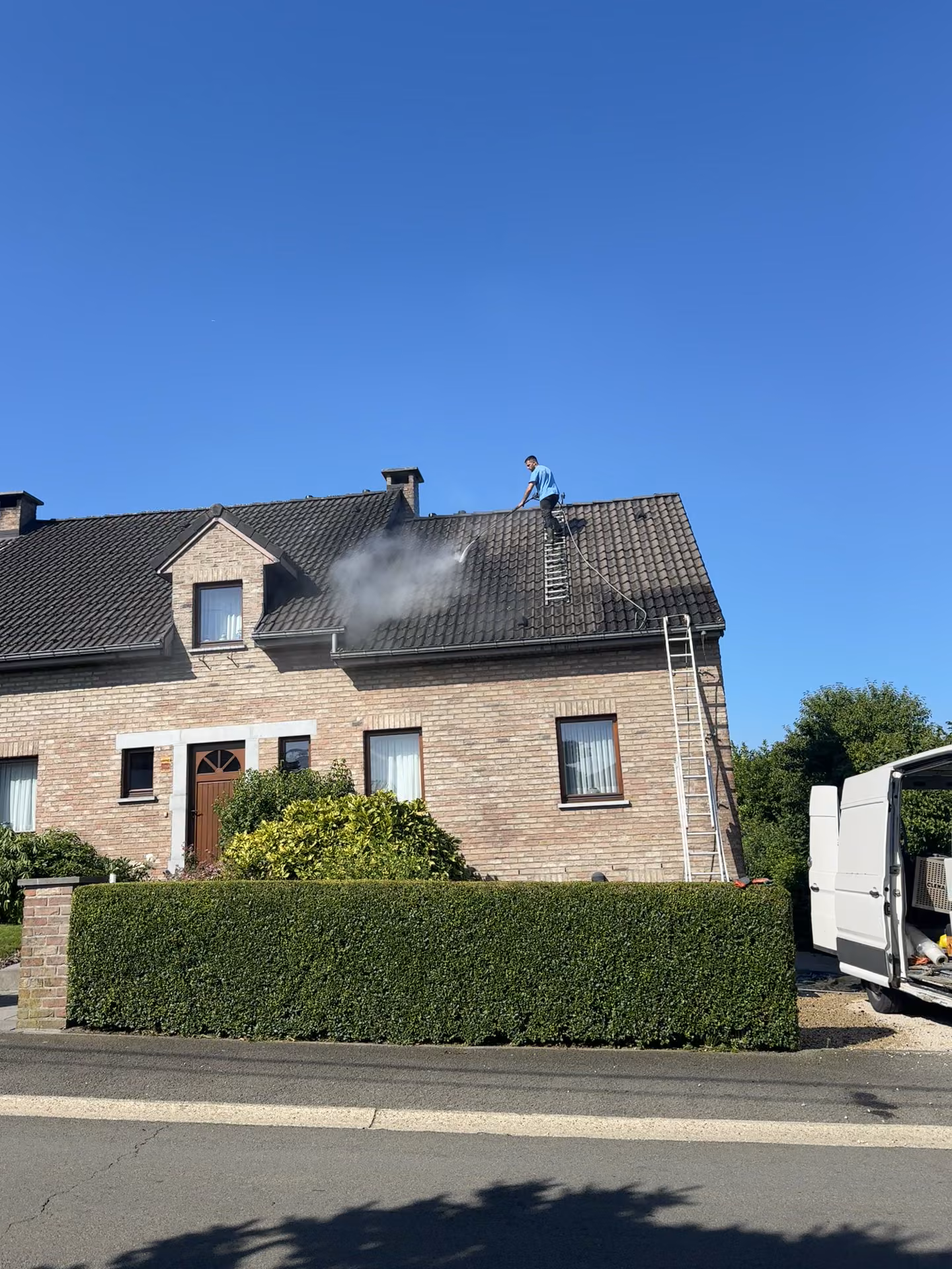 Démoussage à la vapeur d'une toiture de maison en briques