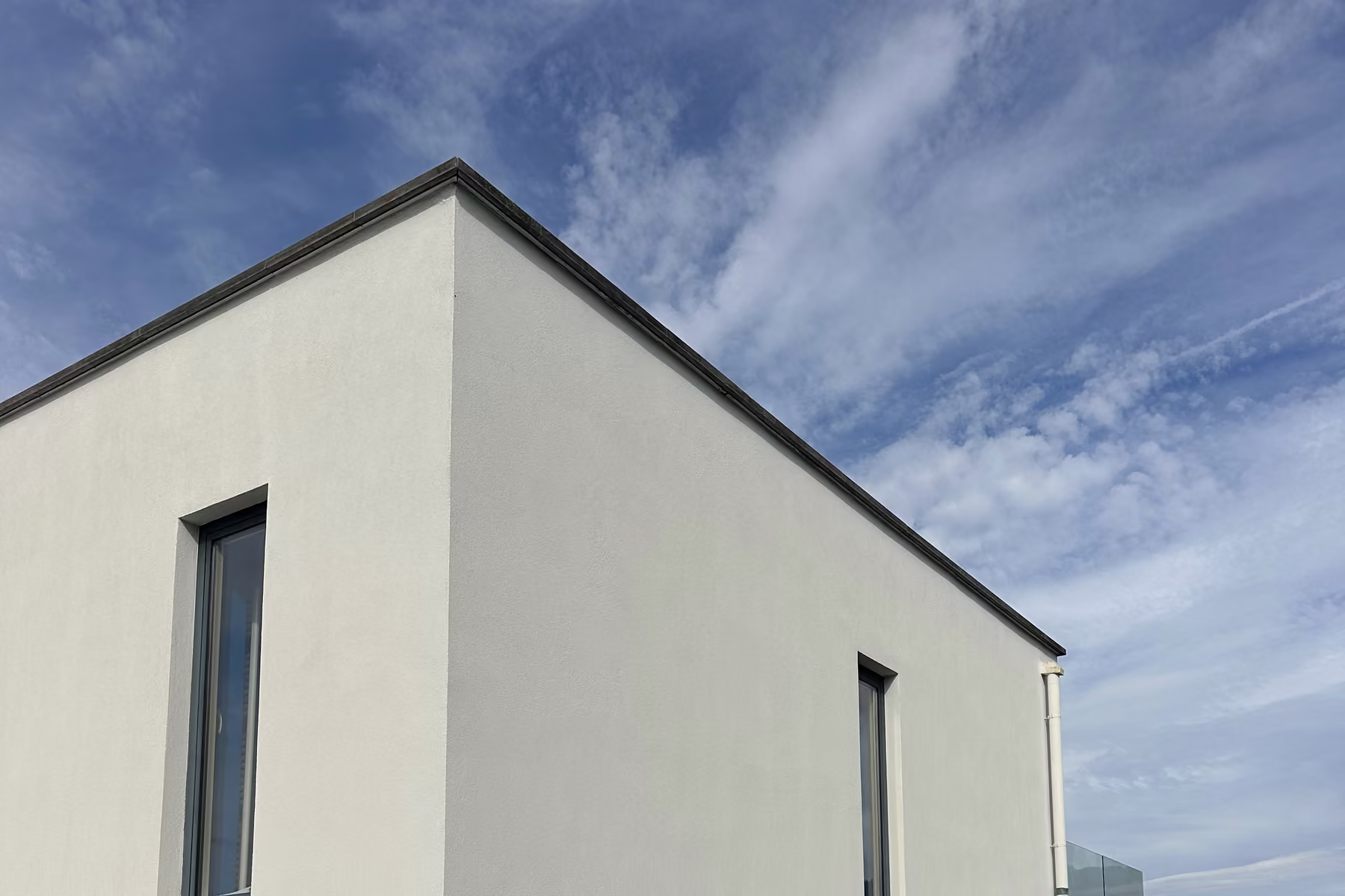 Façade en crépi blanc propre après nettoyage, sous un ciel bleu