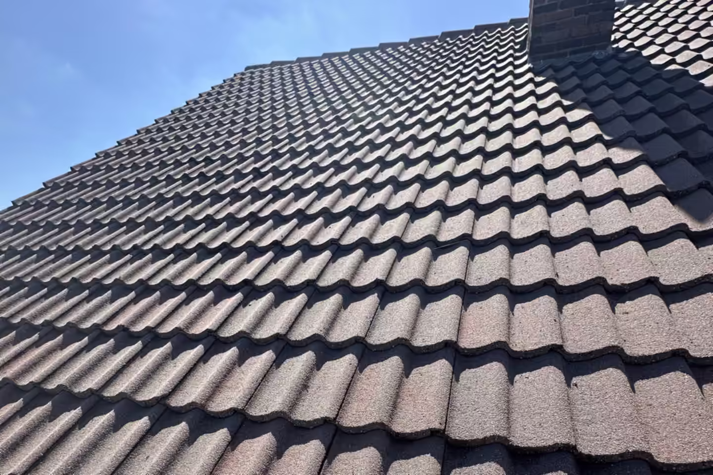 Toiture en tuiles propre après démoussage, sous un ciel bleu