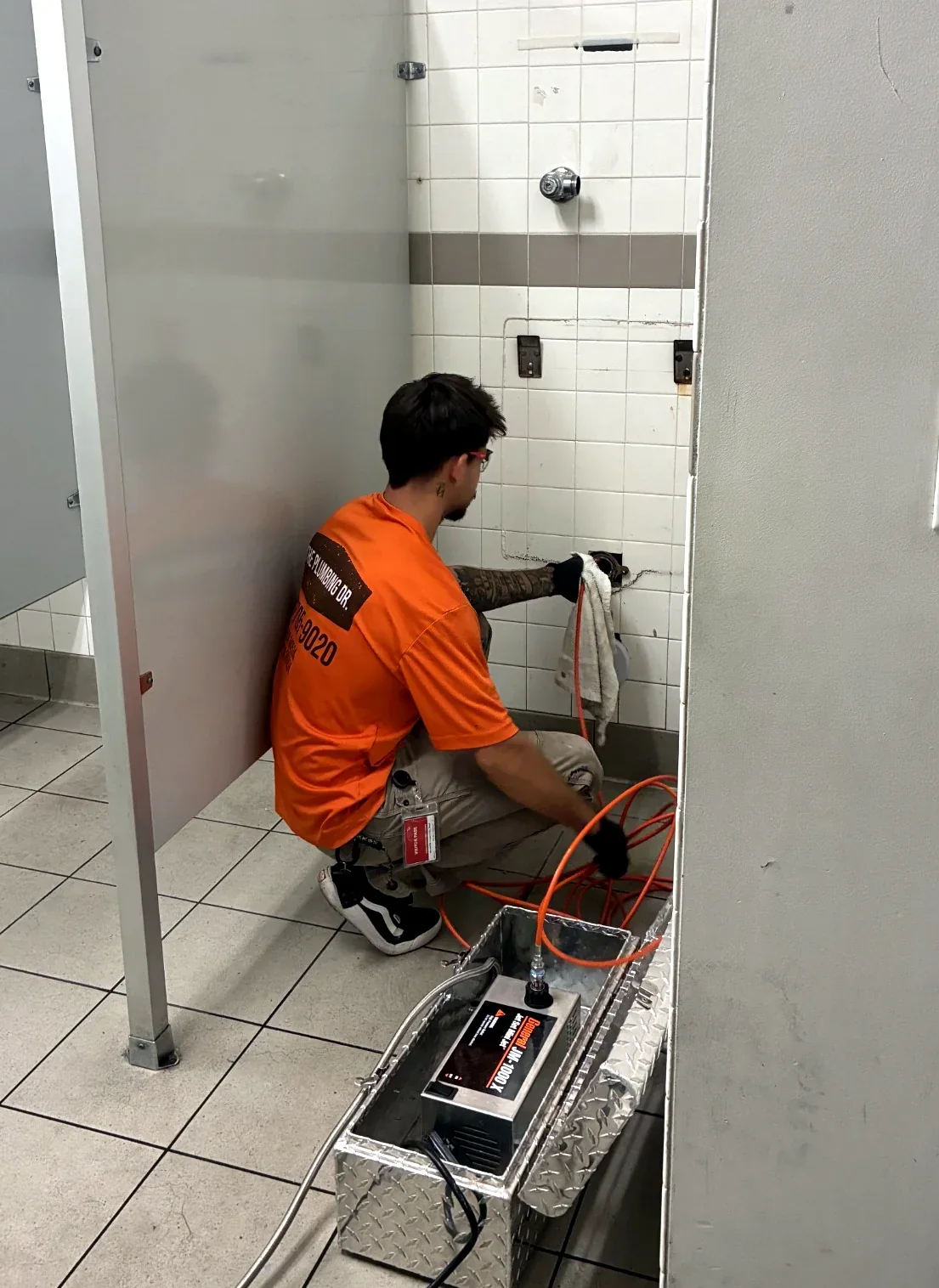 The Plumbing Dr. technician running a drain line jetter in a commercial restroom