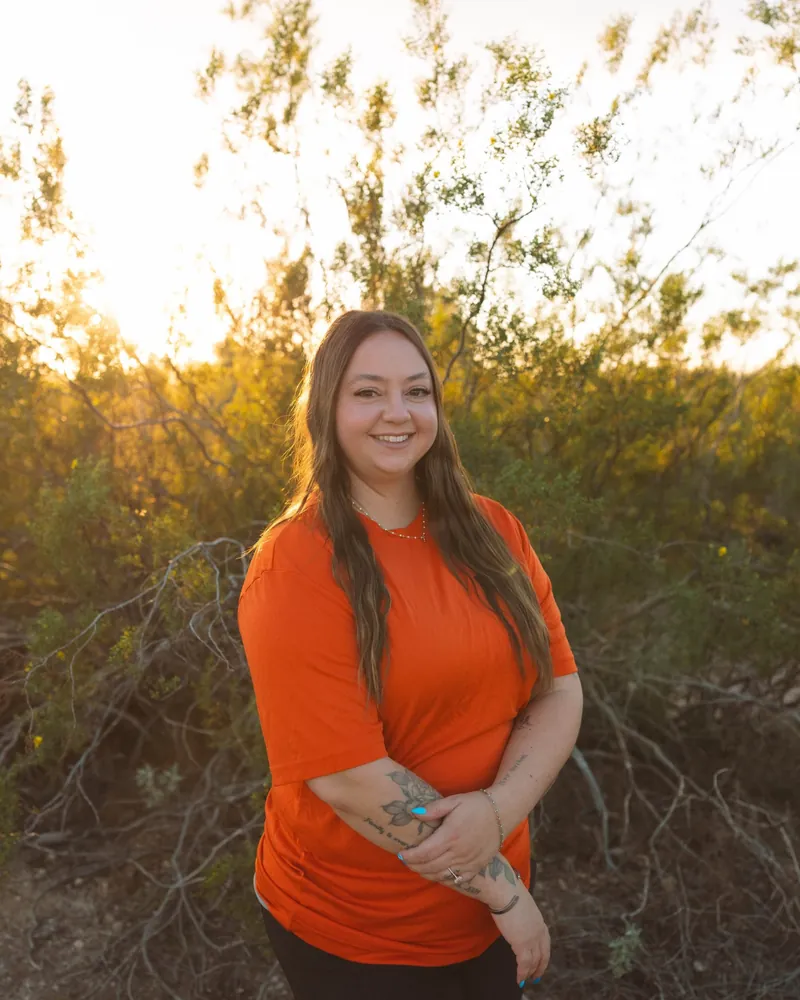 Taylor, office and admin at The Plumbing Dr., in an orange company shirt outdoors in the Arizona desert
