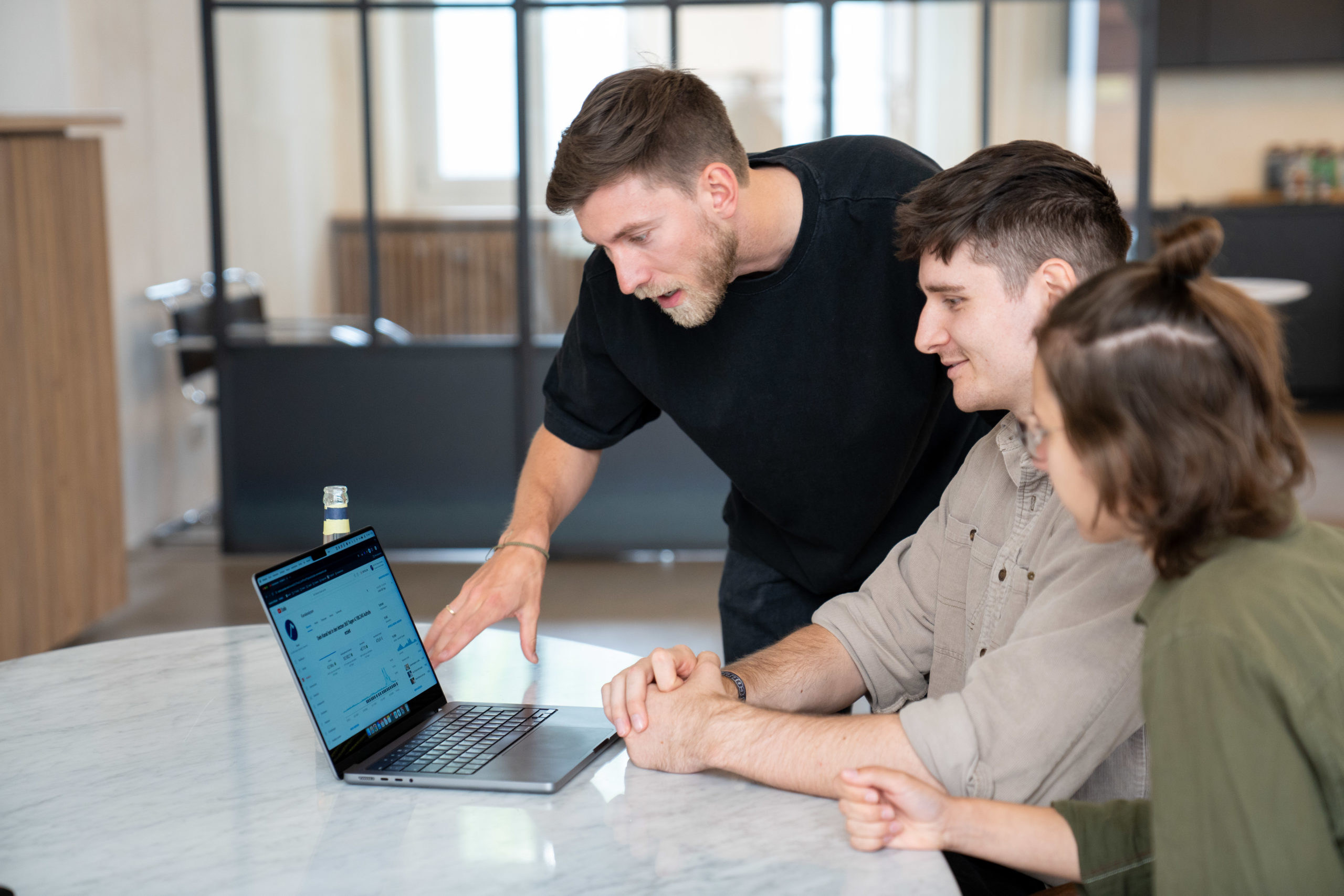 Drei Menschen sitzen vor einem Laptop und besprechen Strategien für YouTube-Marketing für Unternehmen