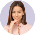 Portrait of a young woman with long brown hair wearing a light pink blouse, resting her chin on her hand.