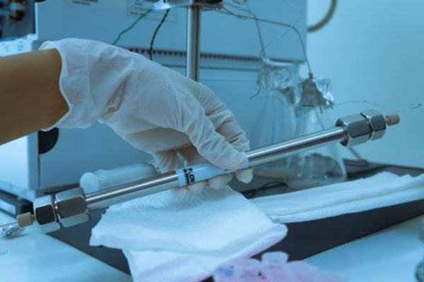 Gloved scientist handling a chromatography column used for protein aggregate analysis