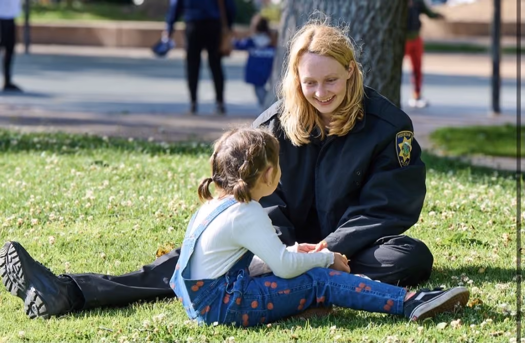A Mountain View police officer sitting with a child on the grass