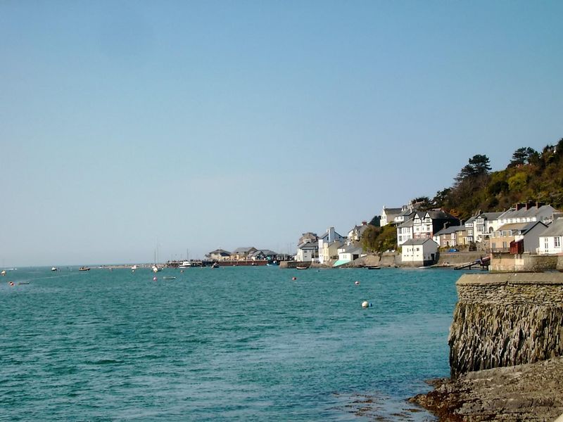 A harbor town at low tide with boats resting on the sand beneath a hillside