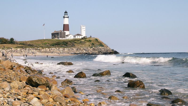 A lighthouse standing on a rocky New England shoreline