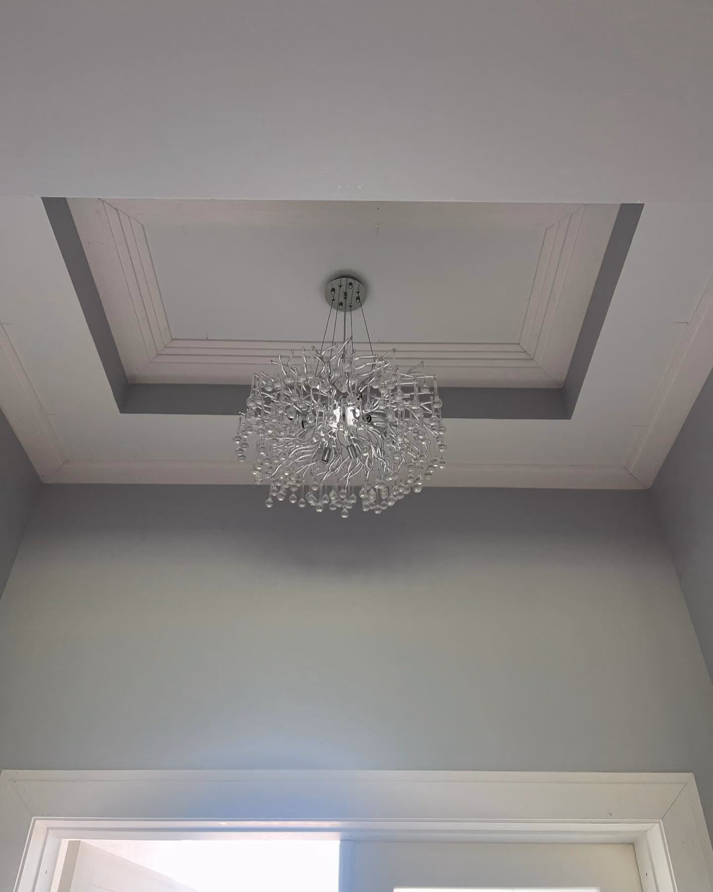 Installed crystal chandelier illuminating a finished residential interior.