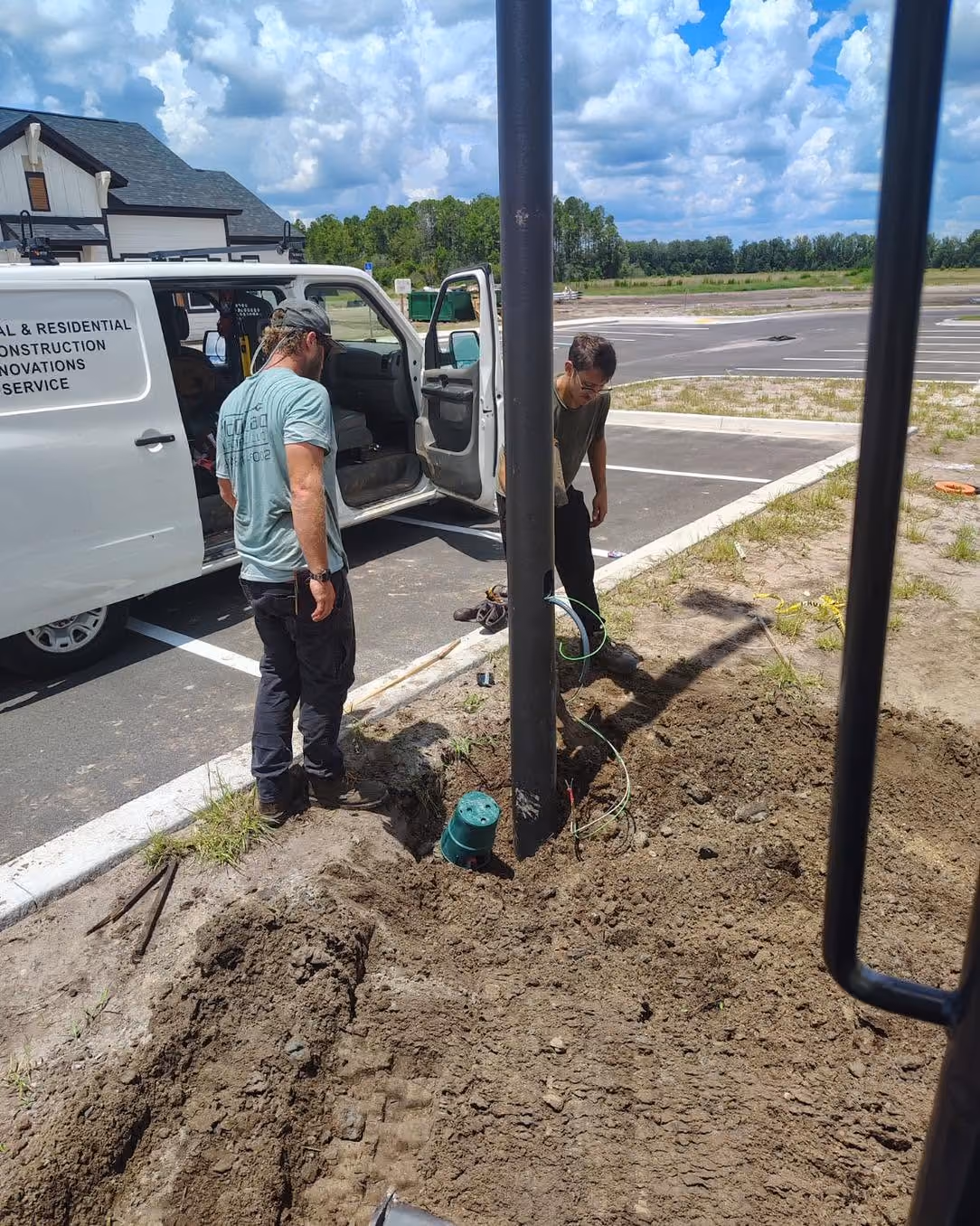 Electricians installing electrical wiring at a commercial parking lot.