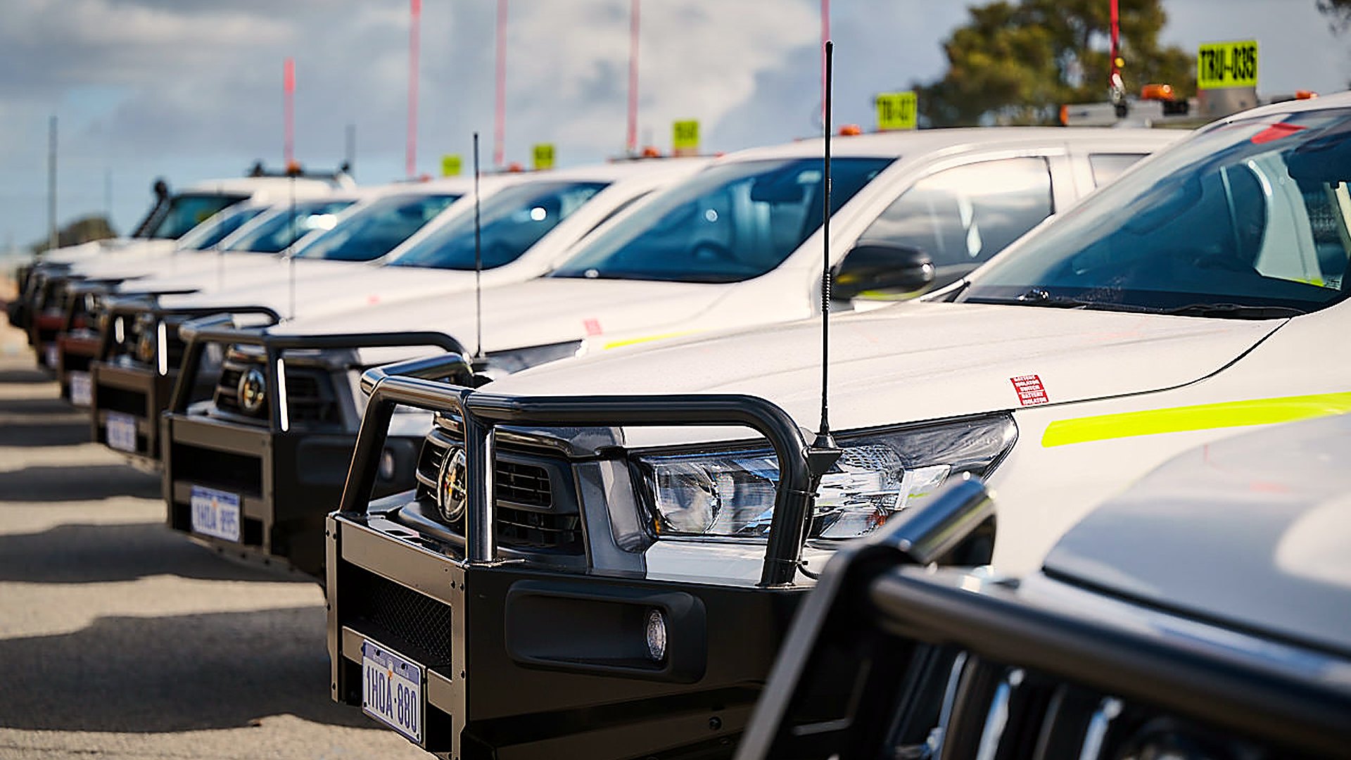 Row of mine-spec four wheel drive utes with bull bars and safety flags