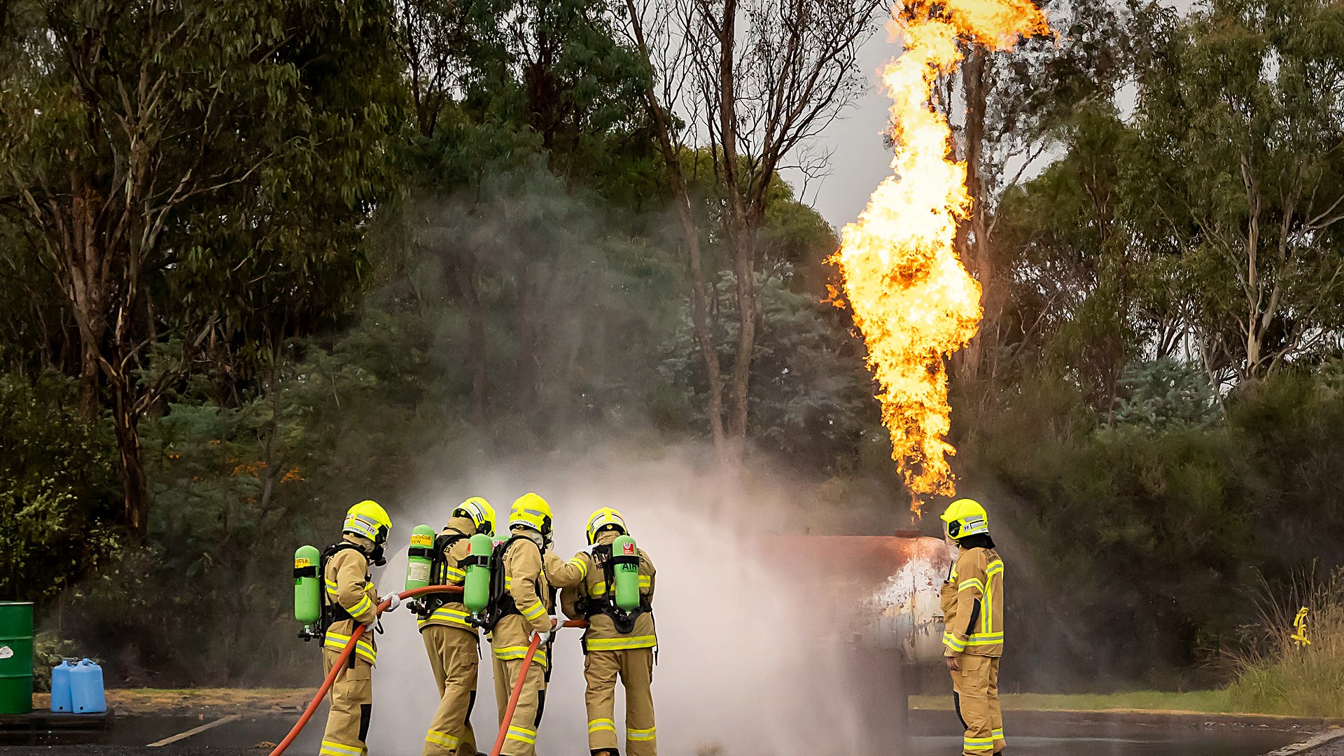 Firefighting trainees in breathing apparatus extinguishing a live fire