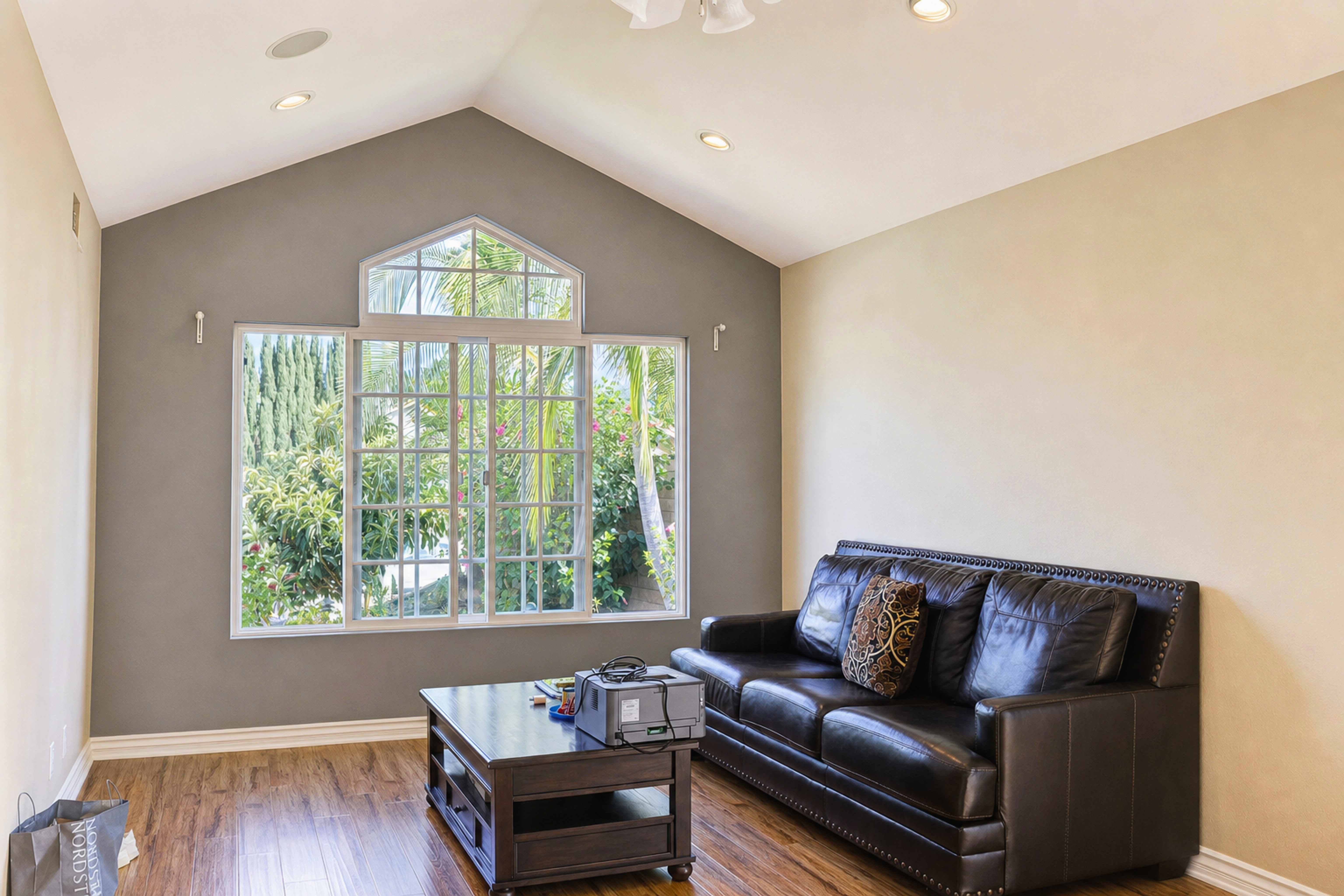 Living room with vaulted ceiling, tall picture window and leather seating, Anaheim short-term rental