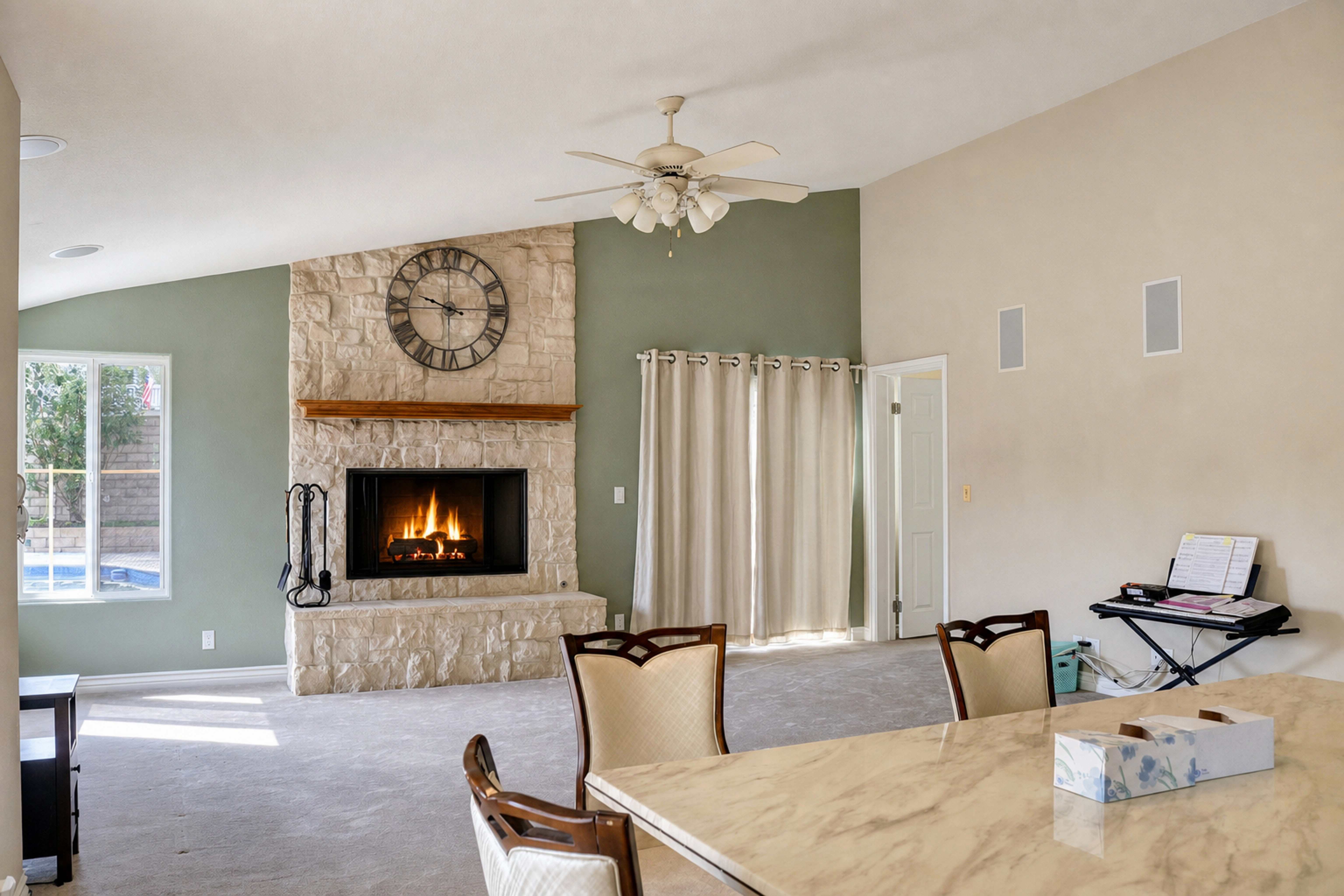 Family room with stone fireplace and ceiling fan seen past the dining table, Anaheim rental