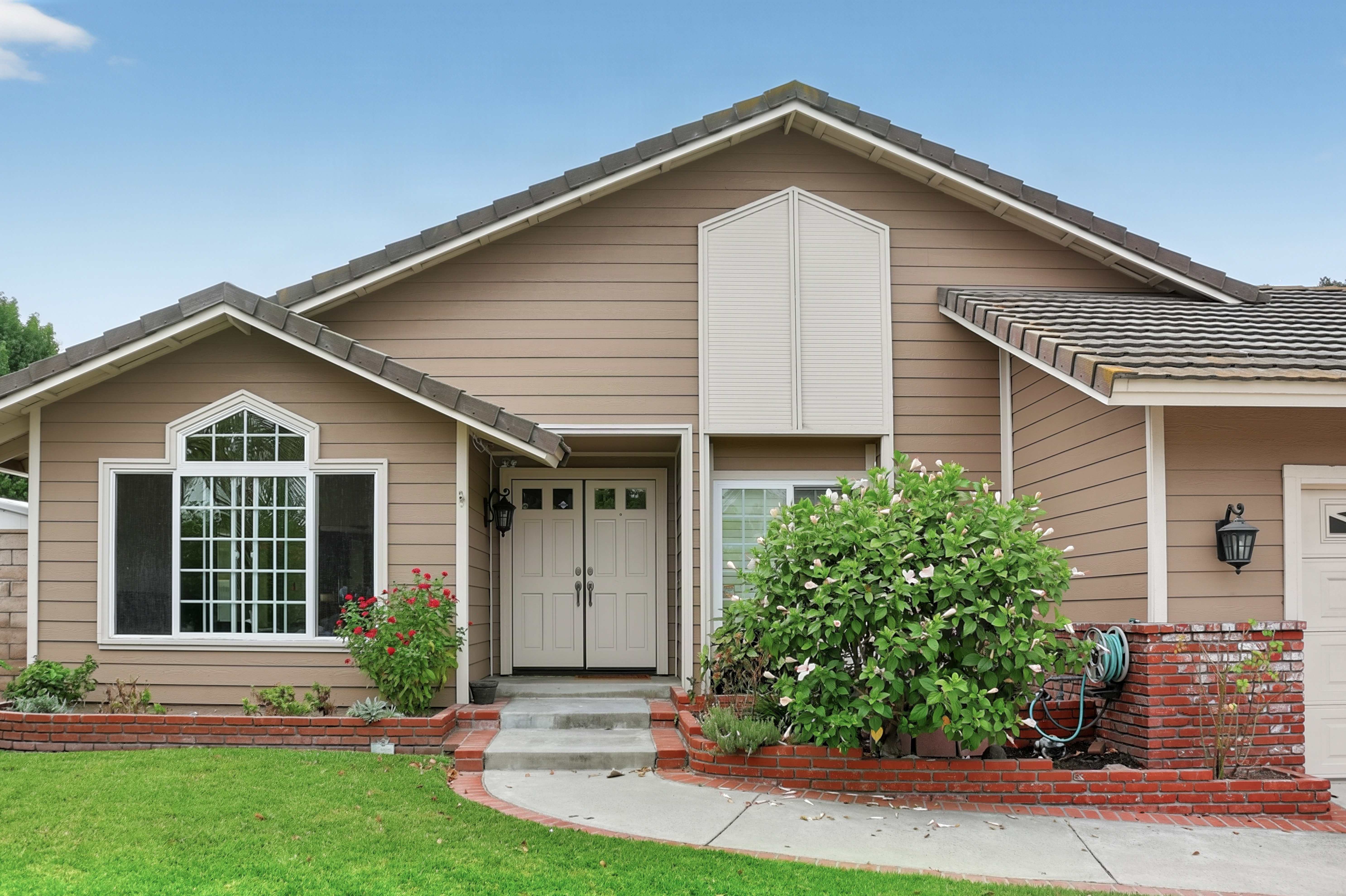 Front exterior of a single-story Anaheim home with two-car garage, brick trim and manicured lawn