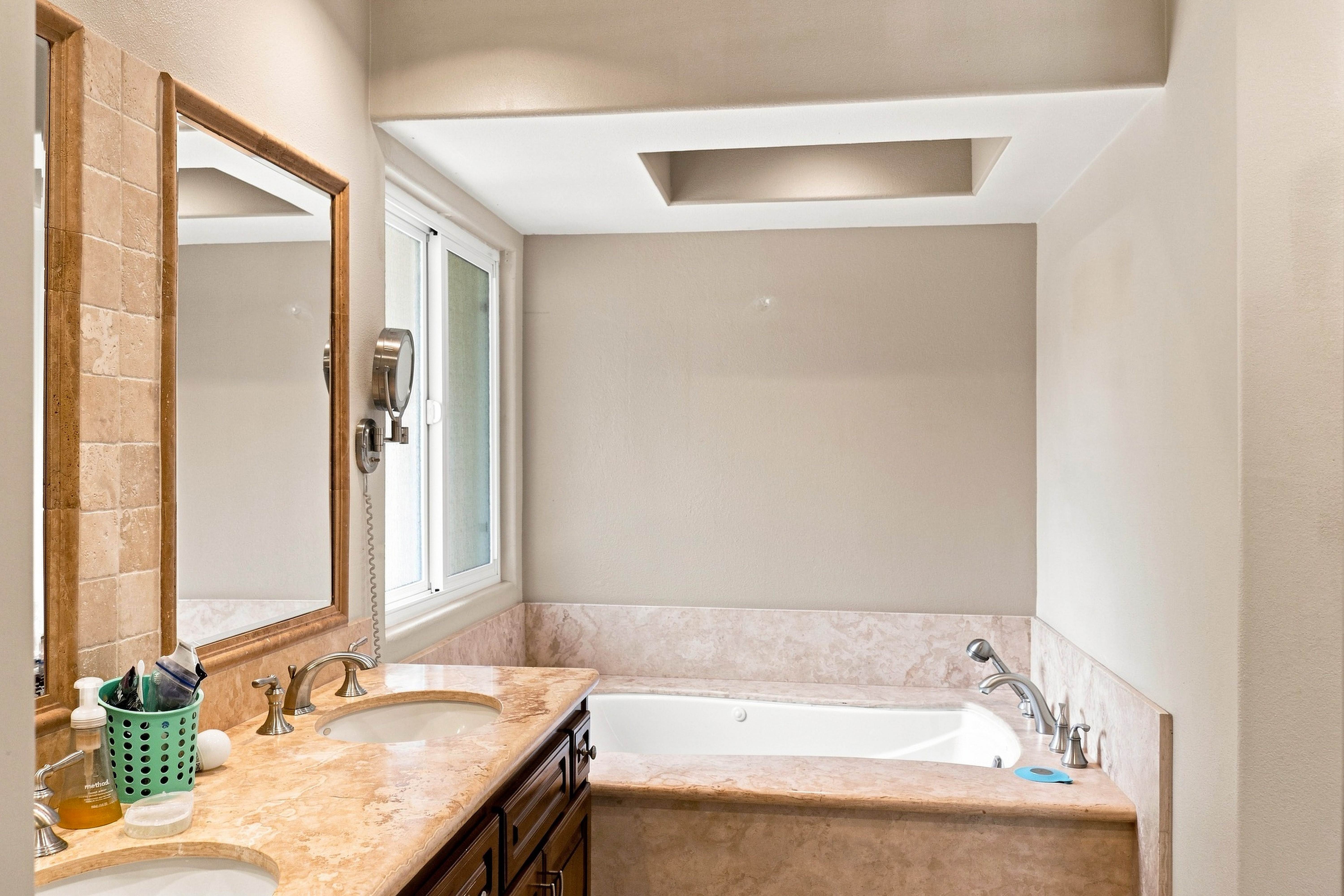 Bathroom vanity with framed mirror and tiled surround beside the tub, Anaheim rental home