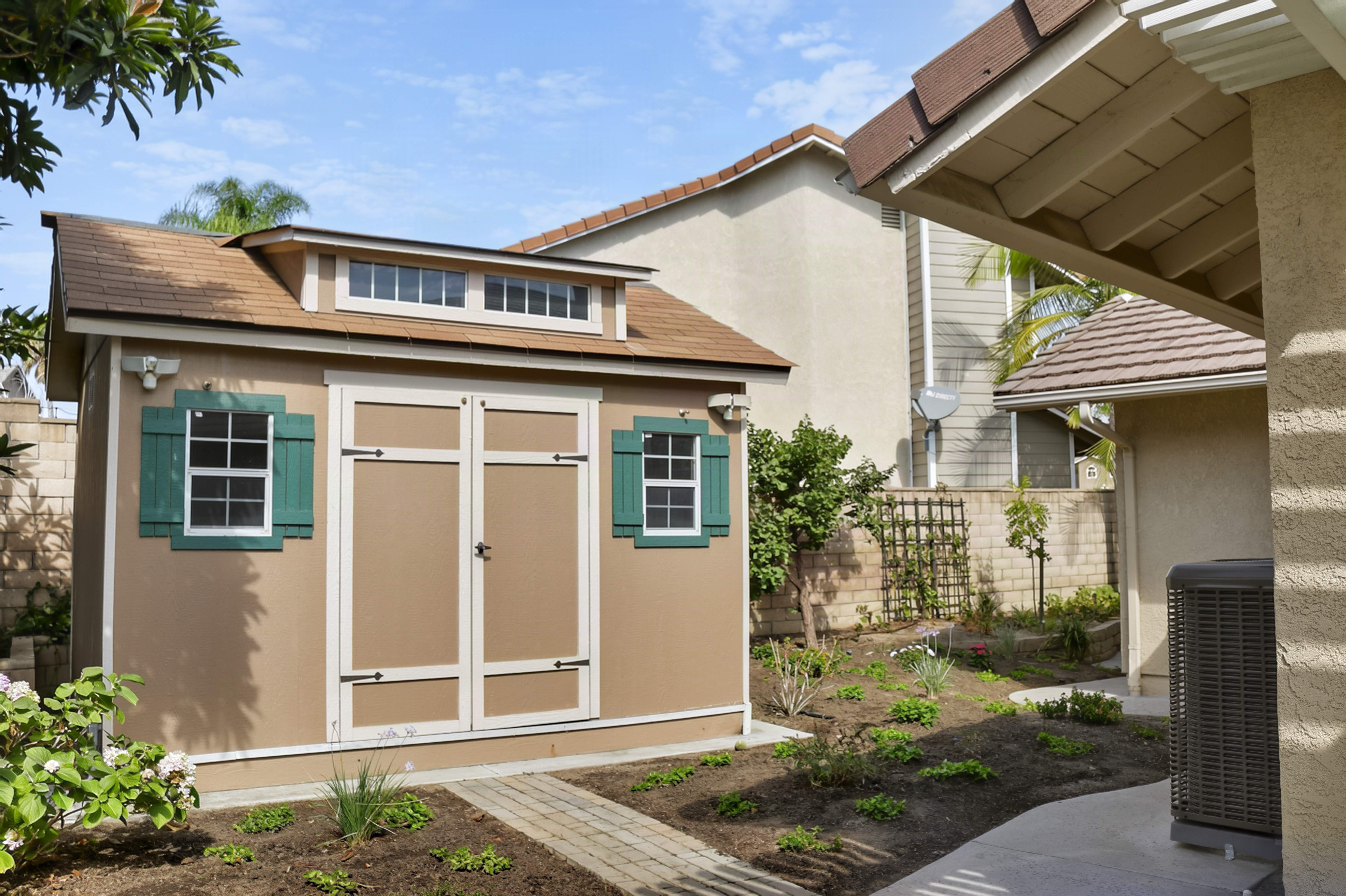 Backyard outbuilding with green shutters and mature landscaping, Anaheim rental property