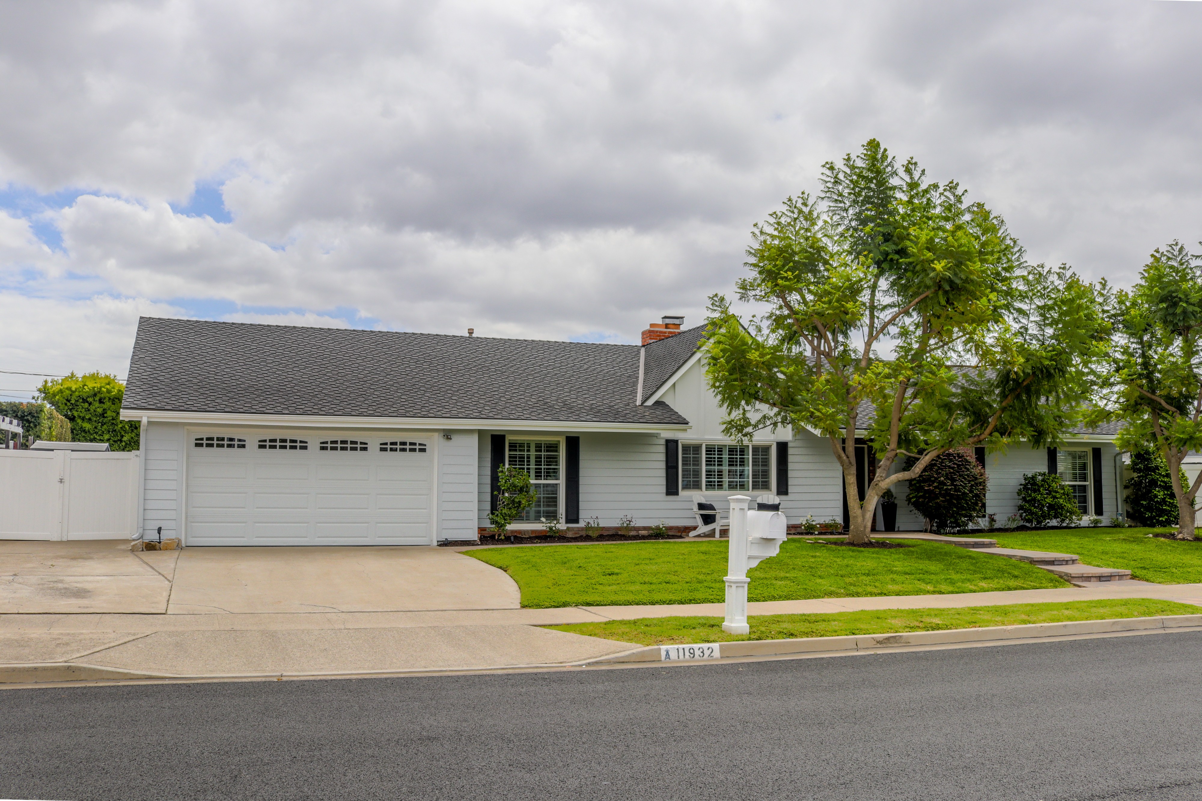 Front exterior of a white single-story ranch home with attached garage and lawn, Tustin listing