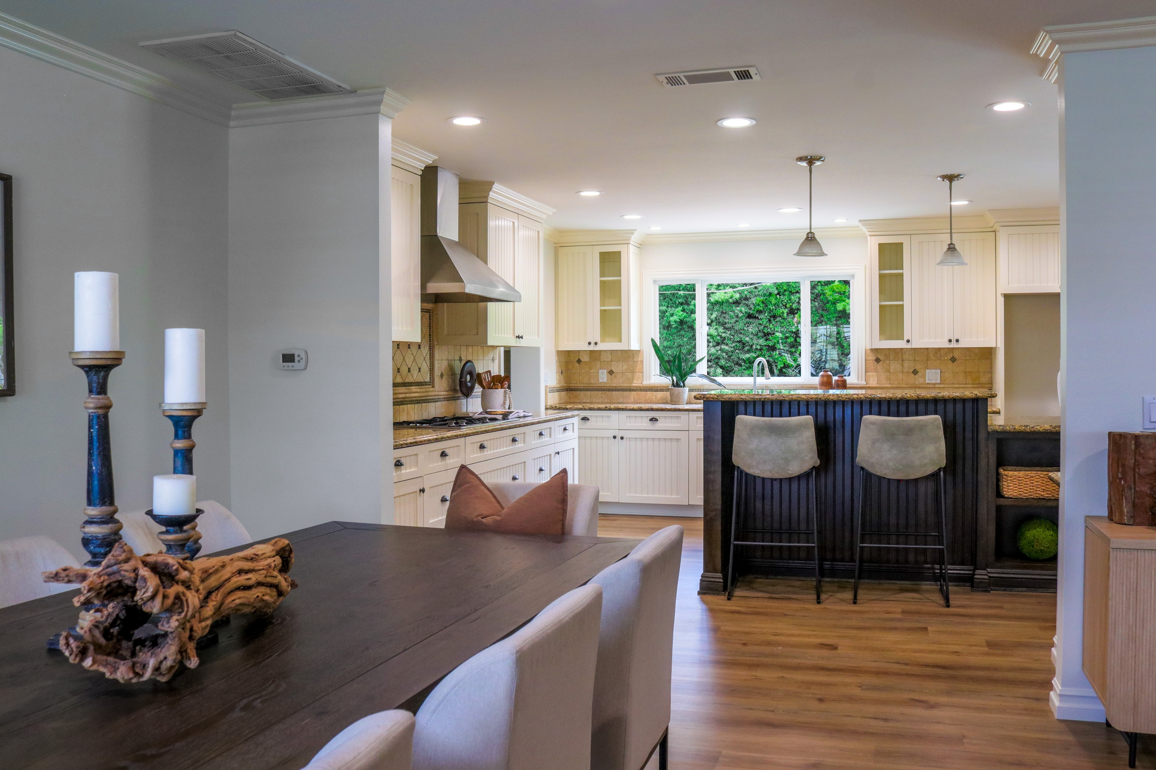 Open-plan dining and kitchen with driftwood centerpiece and bar stools, Tustin listing