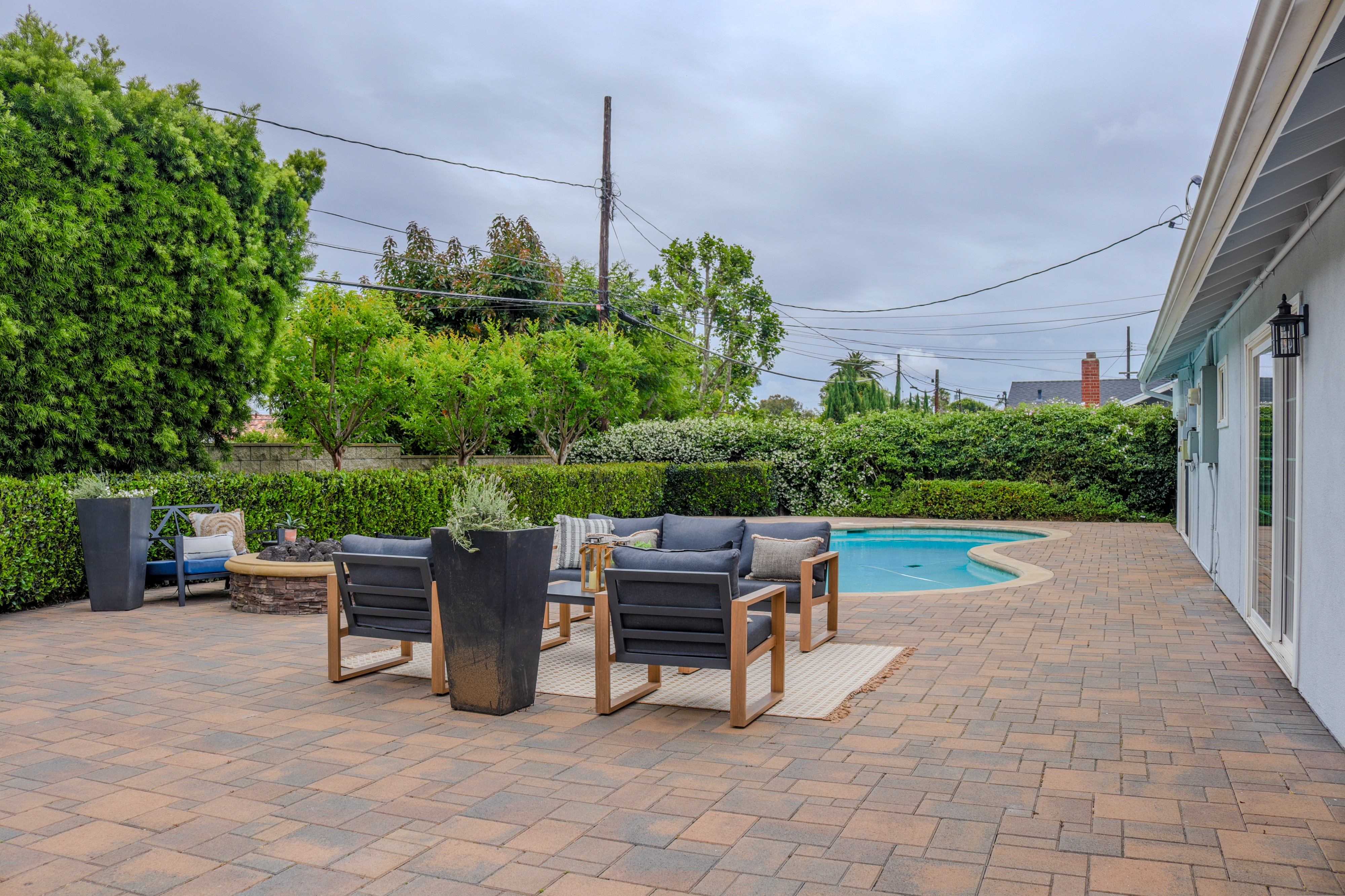 Modern outdoor lounge area by pool with beige sofas, umbrella, and ocean view in the background.