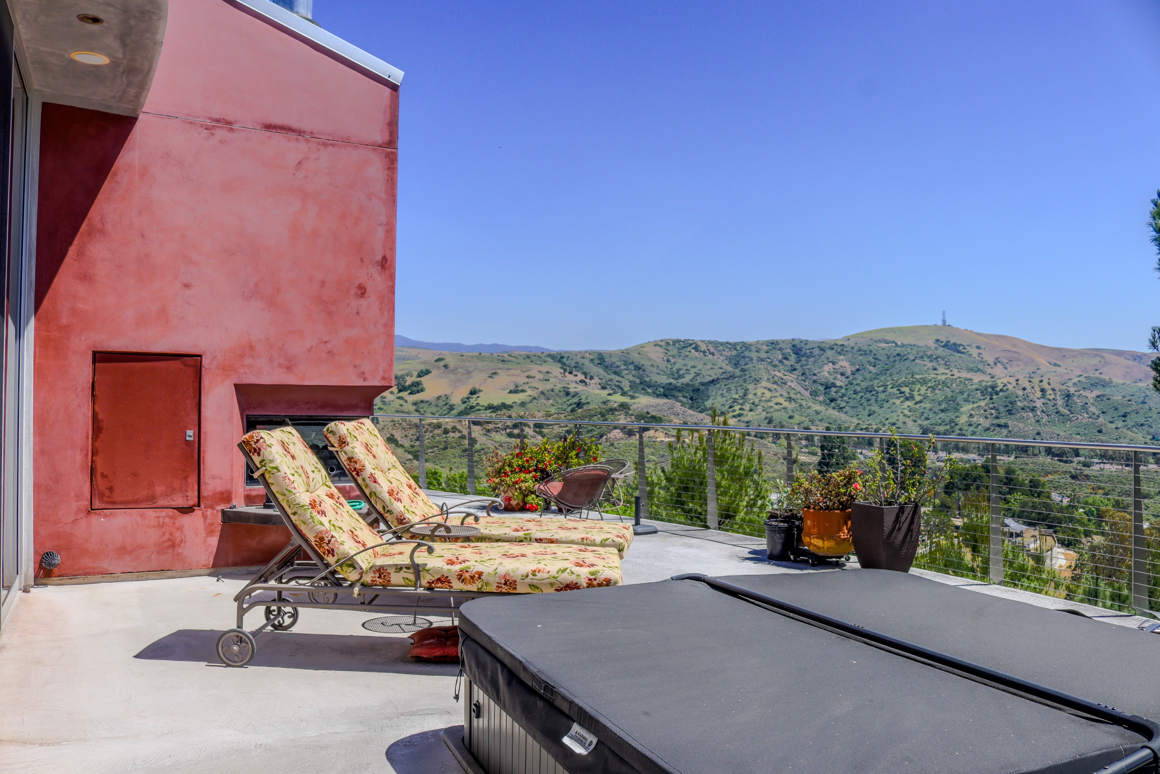 Poolside loungers against a red stucco wall with hillside views, Tustin luxury home