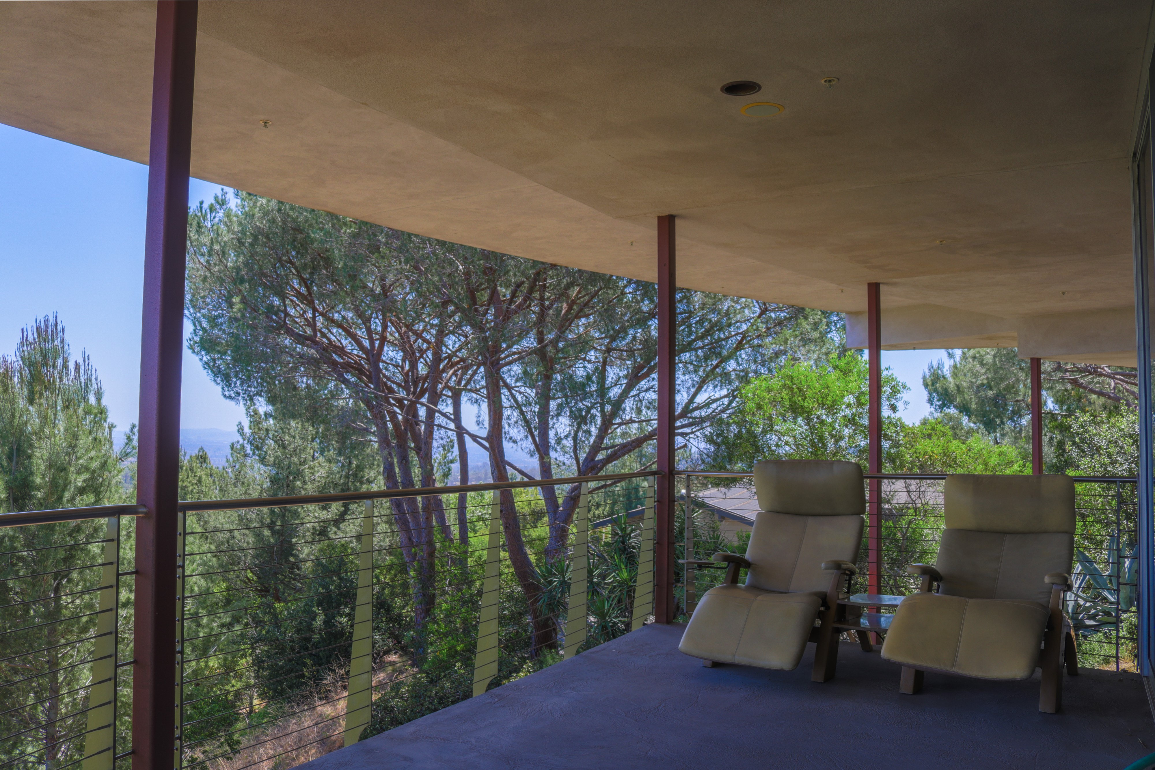 Covered balcony with seating and treetop canyon outlook, Tustin luxury listing