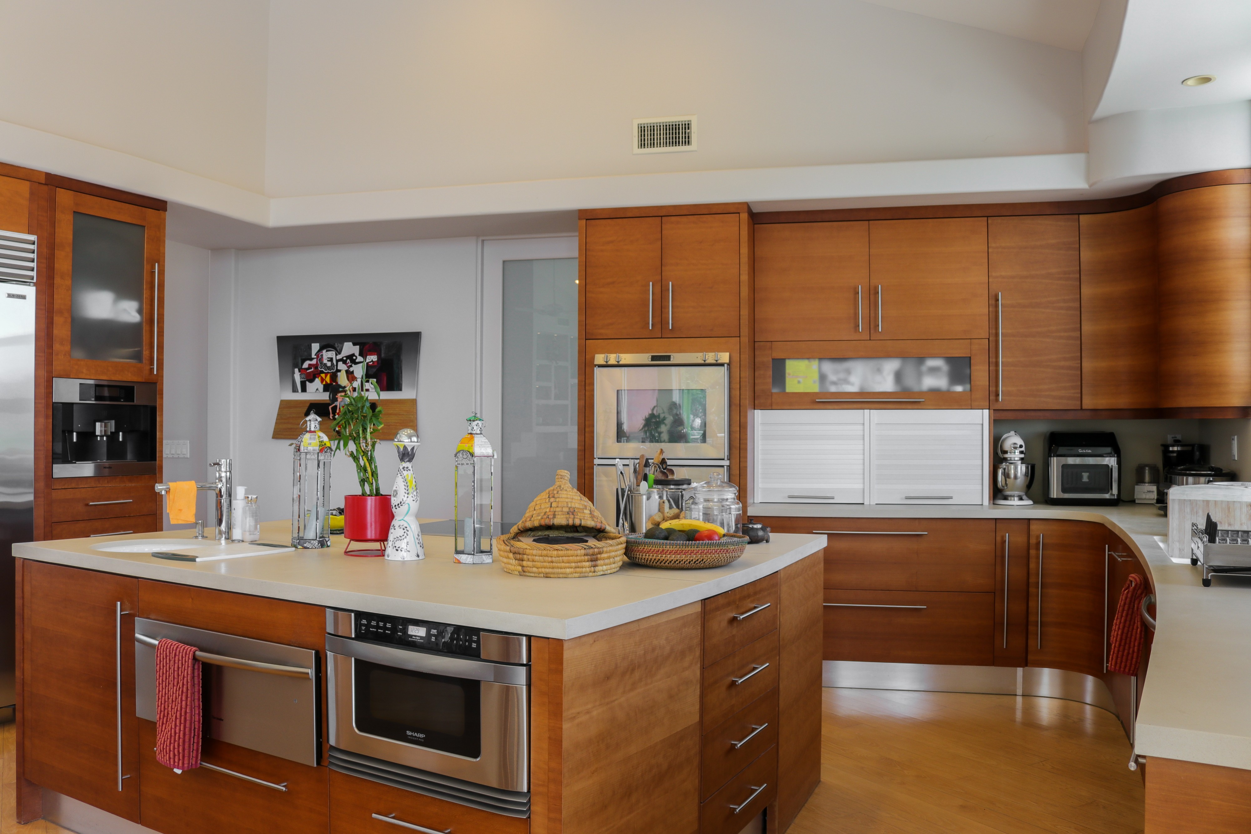 Kitchen with warm wood cabinetry, island and built-in ovens, Tustin hillside home