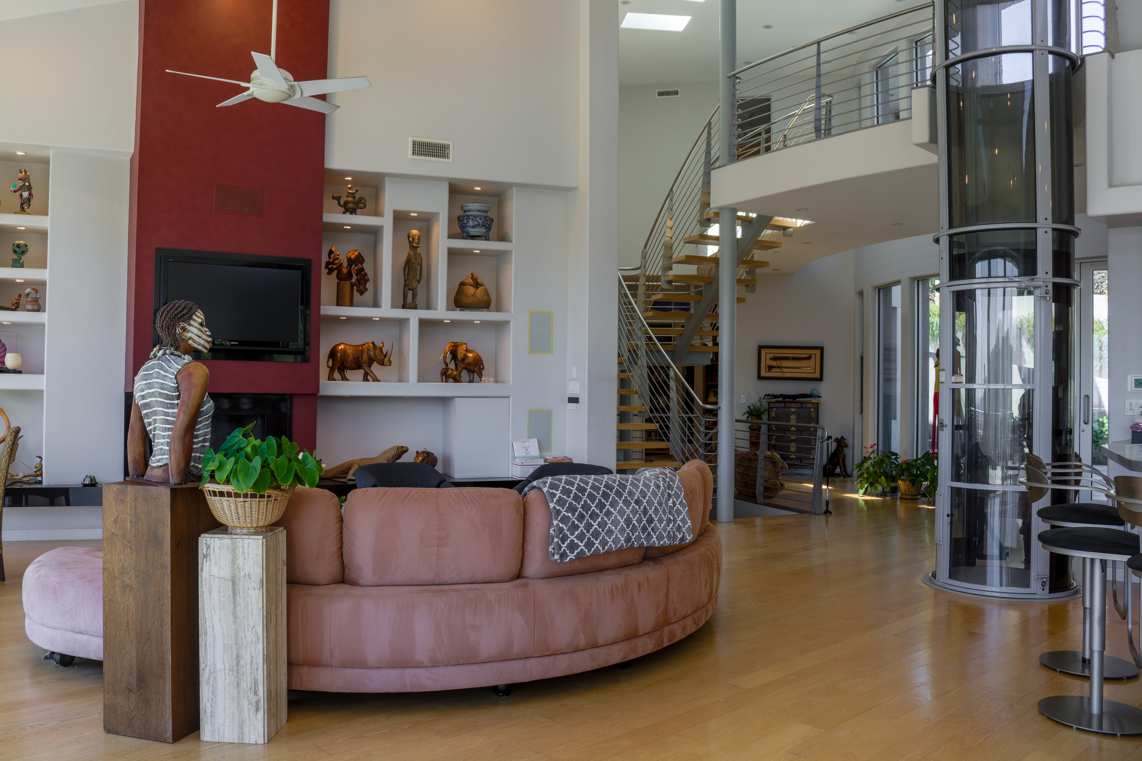 Double-height living room with curved sofa, fireplace and staircase, Tustin luxury home