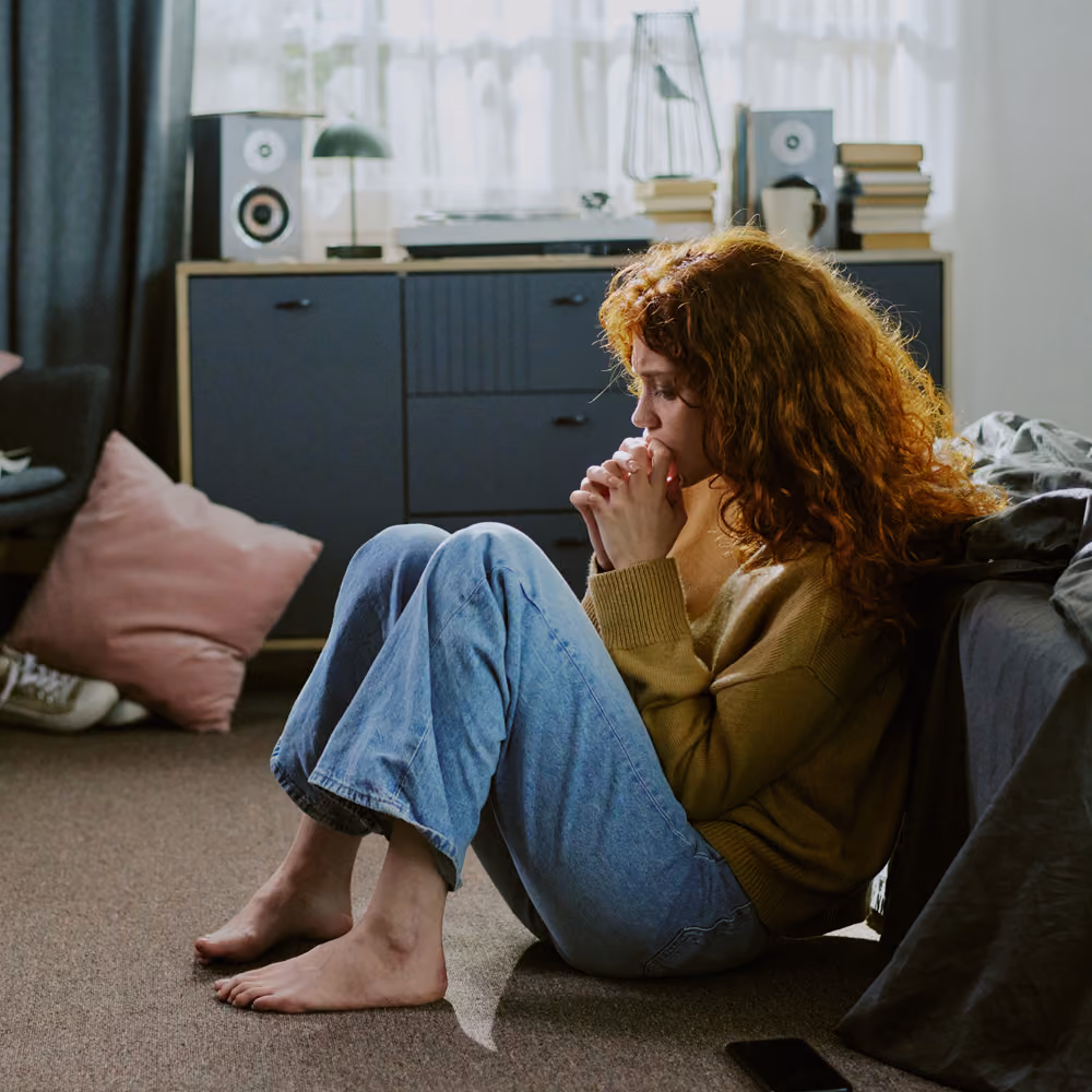 Person sitting by a window in warm light, holding a cup, in a quiet moment of reflection