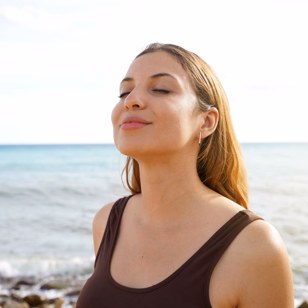 Person with eyes closed, calm expression, bathed in warm sunset light