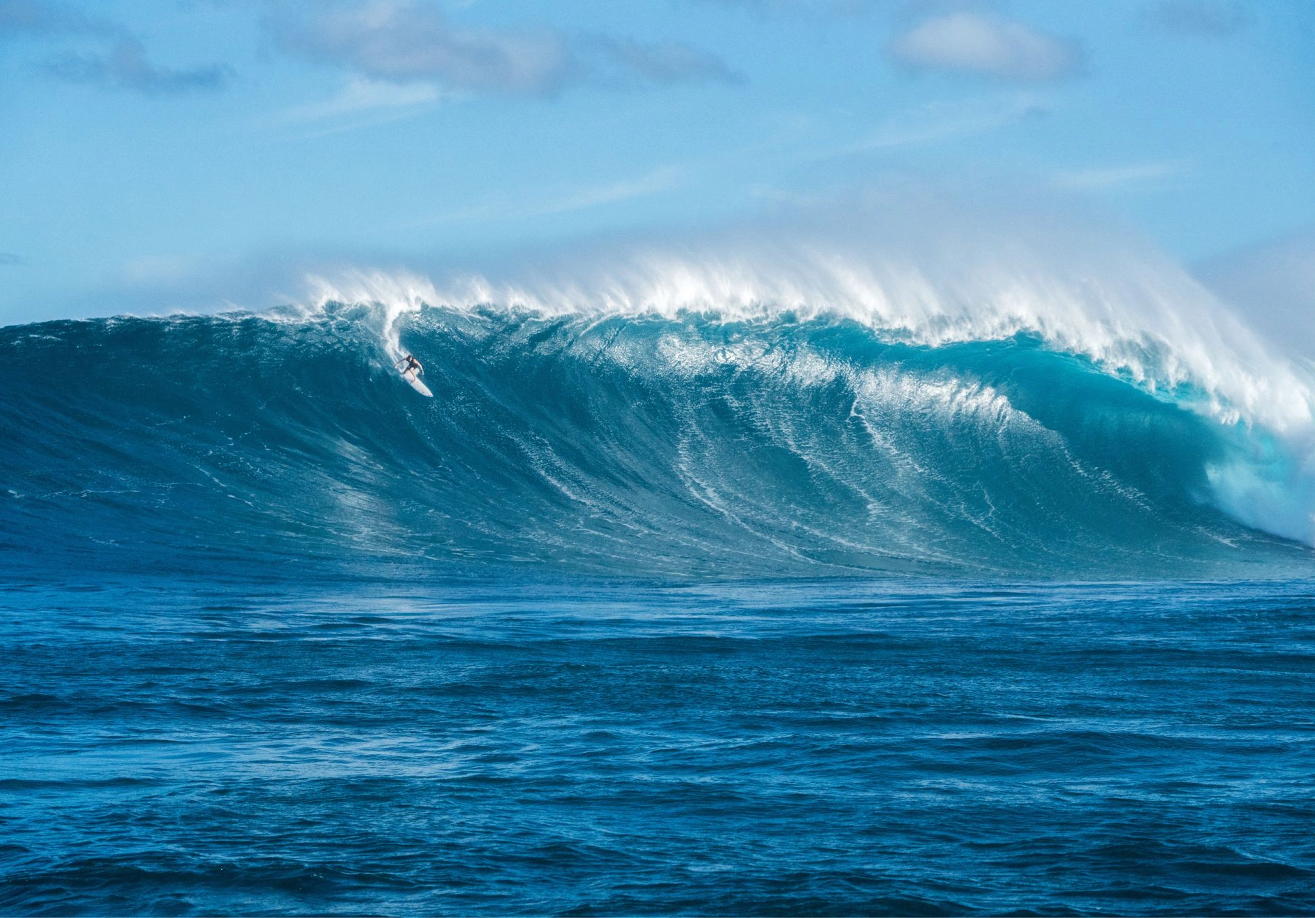 Large blue ocean wave breaking with spray blowing off the lip