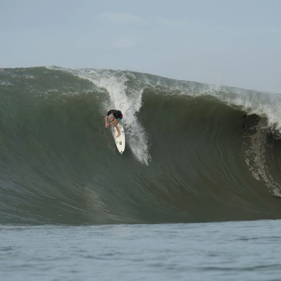 Matt Bromley riding a large wave with whitewater rolling behind him
