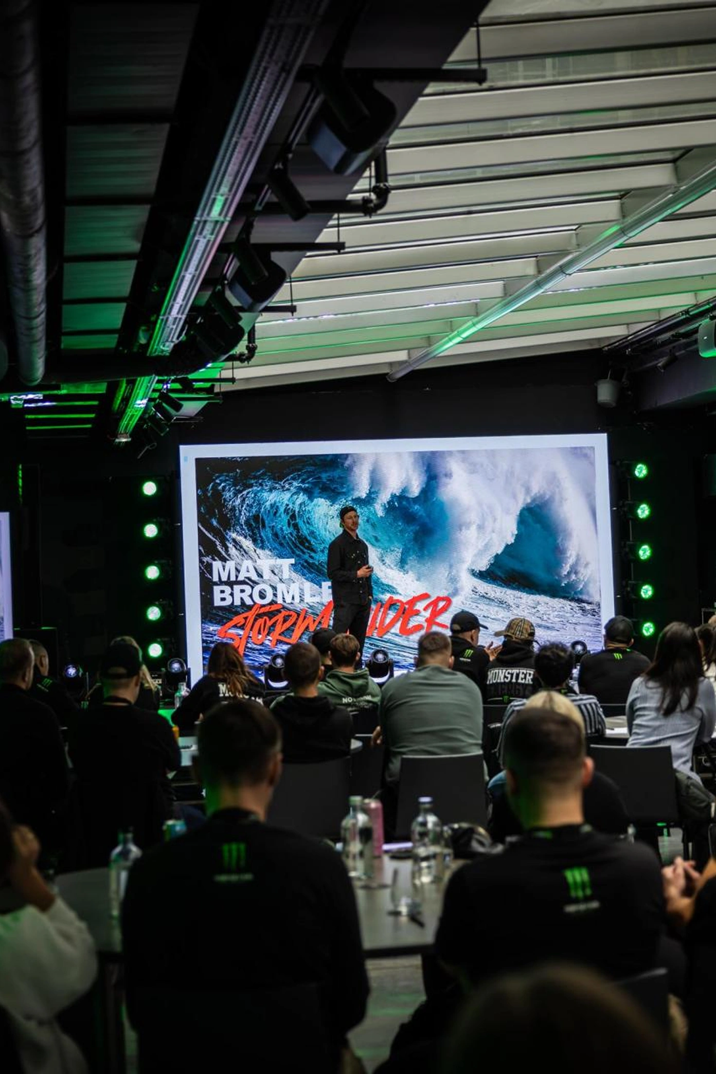 Crowd watching a surf video on the big screen at a conference where Matt Bromley is speaking