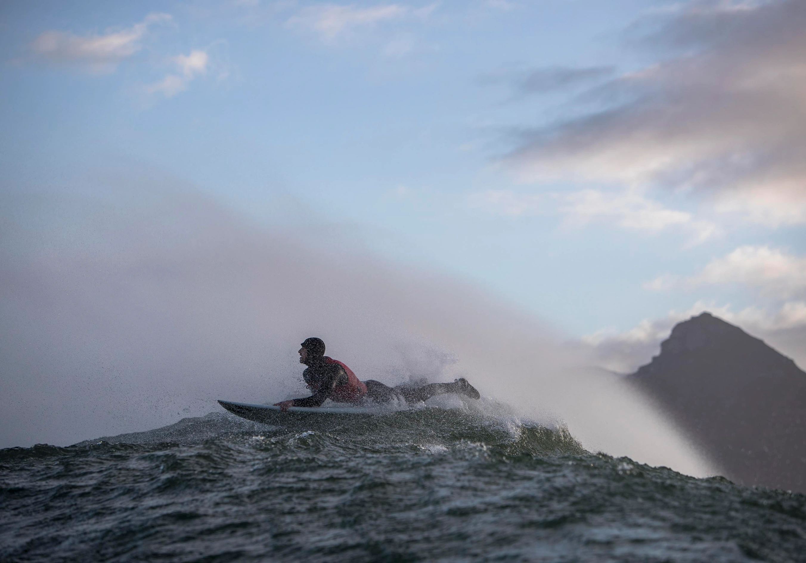Matt Bromley carving across a wave with mountains in the background