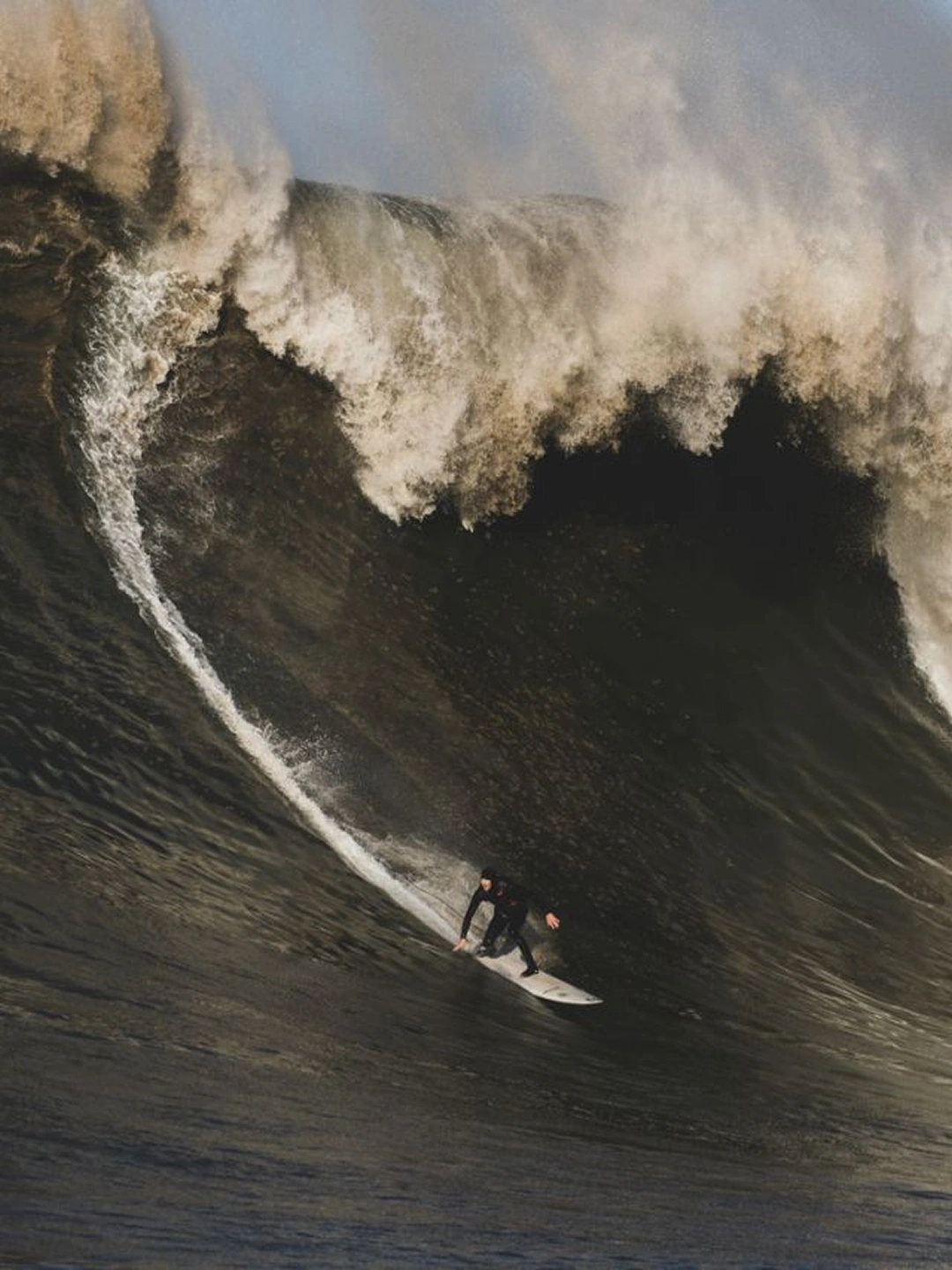 Surfer riding the face of a massive breaking wave