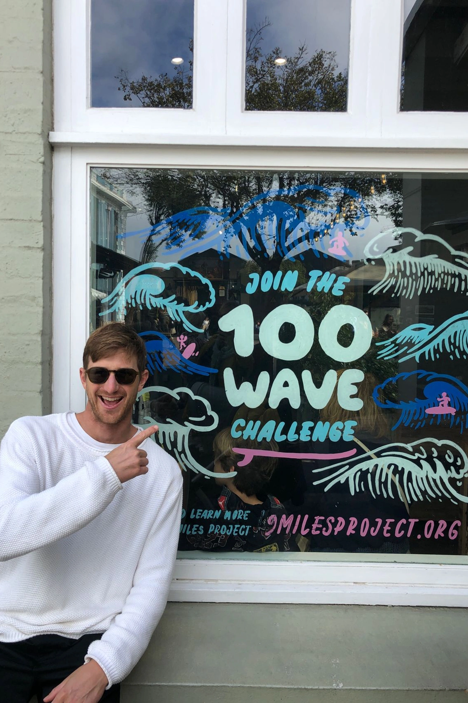 Matt Bromley standing beside a window mural promoting the 100 Wave Challenge