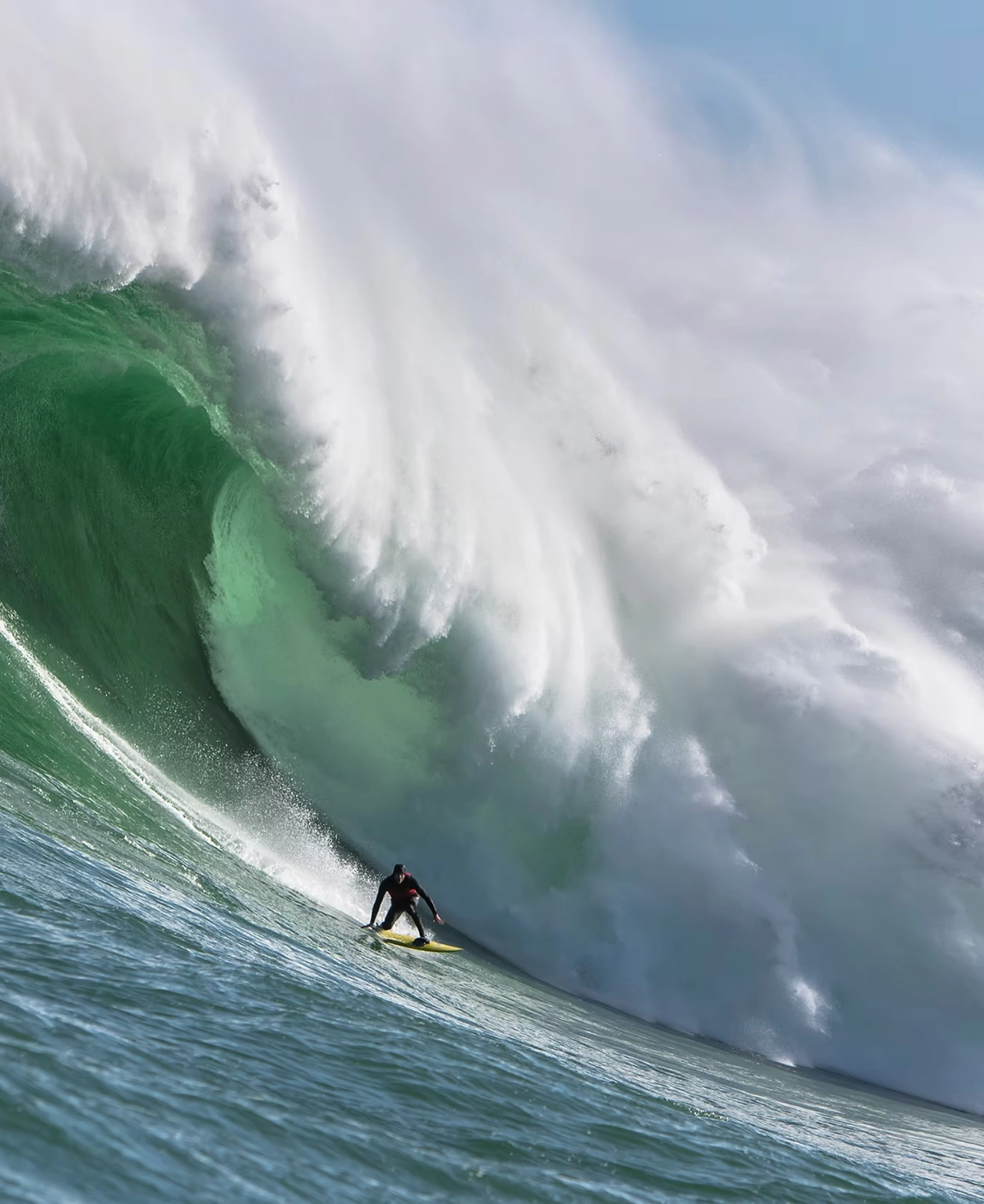 Matt Bromley dropping down the face of a towering green wave