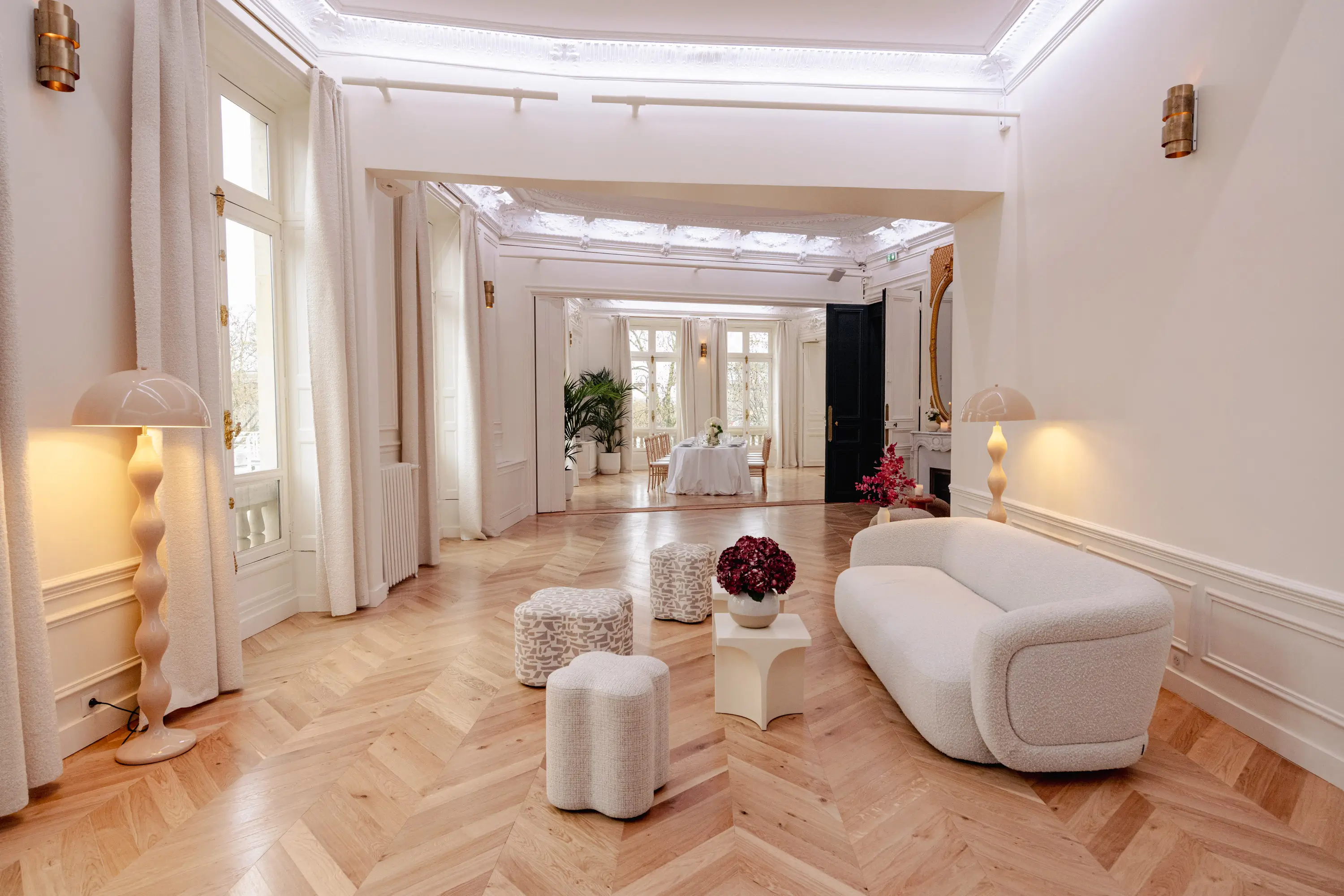 Lounge area in the Presbourg Pavilion with cream bouclé sofa and herringbone parquet, opening onto the adjoining reception room