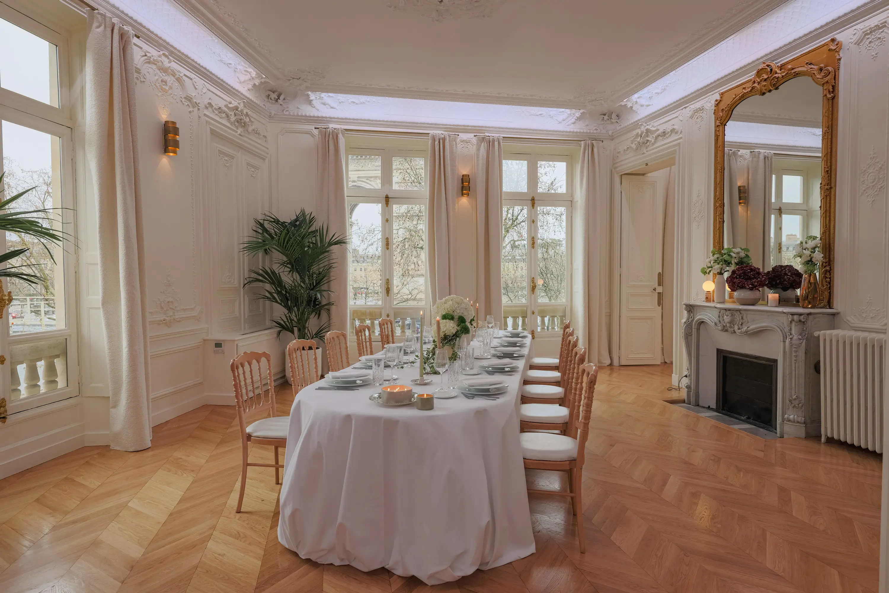 Dining table set for a private dinner in the Étoile Pavilion, with marble fireplace, gilded mirror and views of the Arc de Triomphe