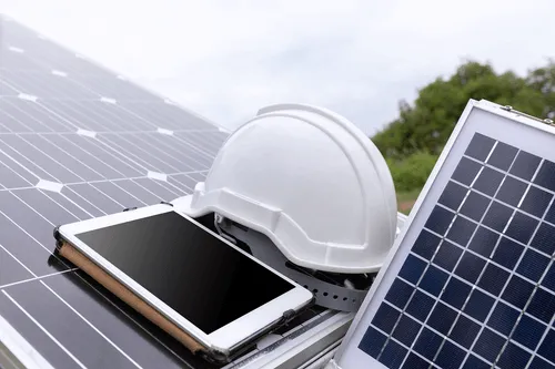 Tablet und Schutzhelm auf Solarmodulen als Symbolbild für die Planung einer Photovoltaikanlage