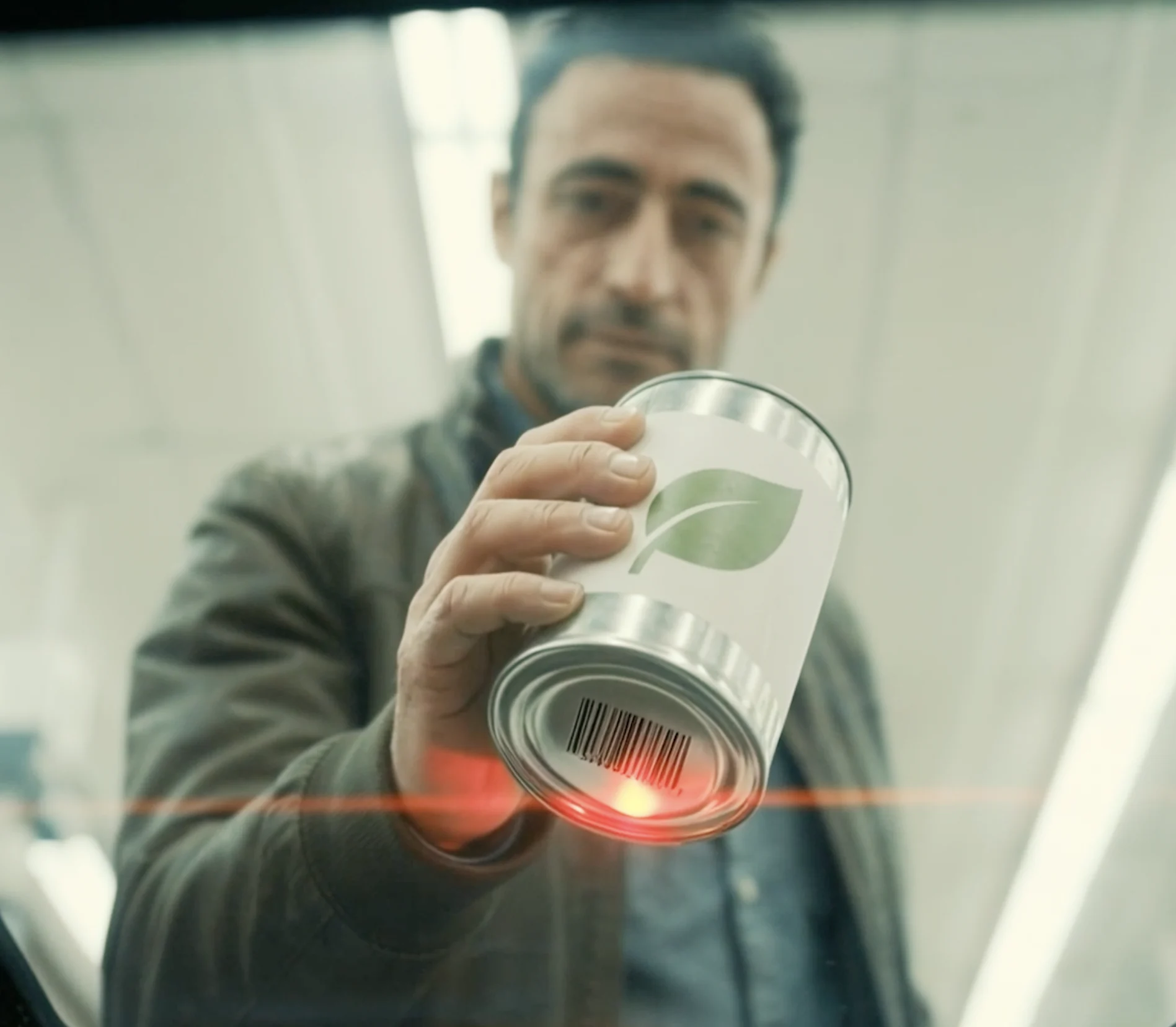A shopper presenting a tinned item to the self-checkout scanner.