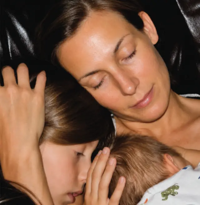 Ute Lemper with eyes closed while embracing her children